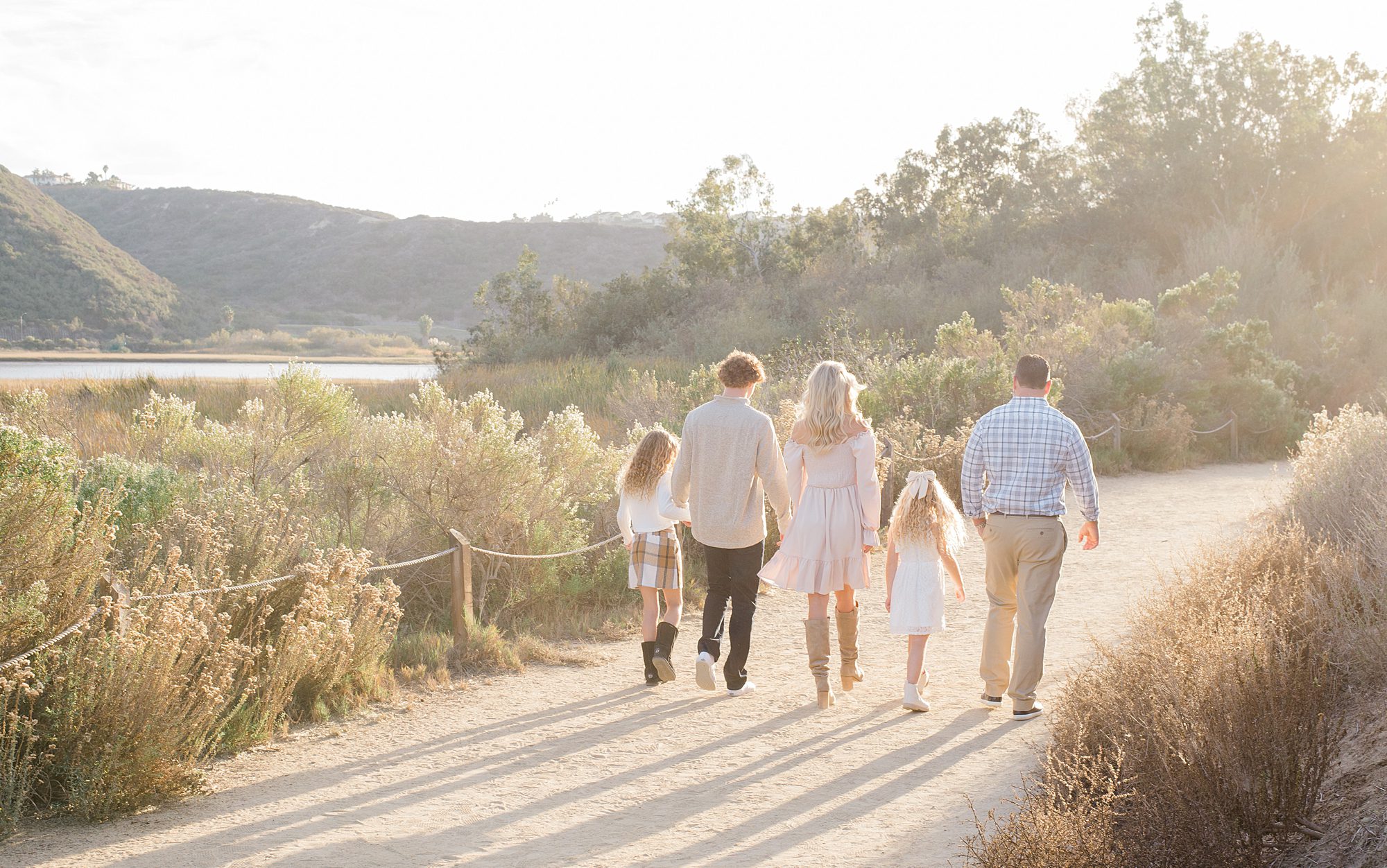 family of five hold hands on trail at Carlsbad CA