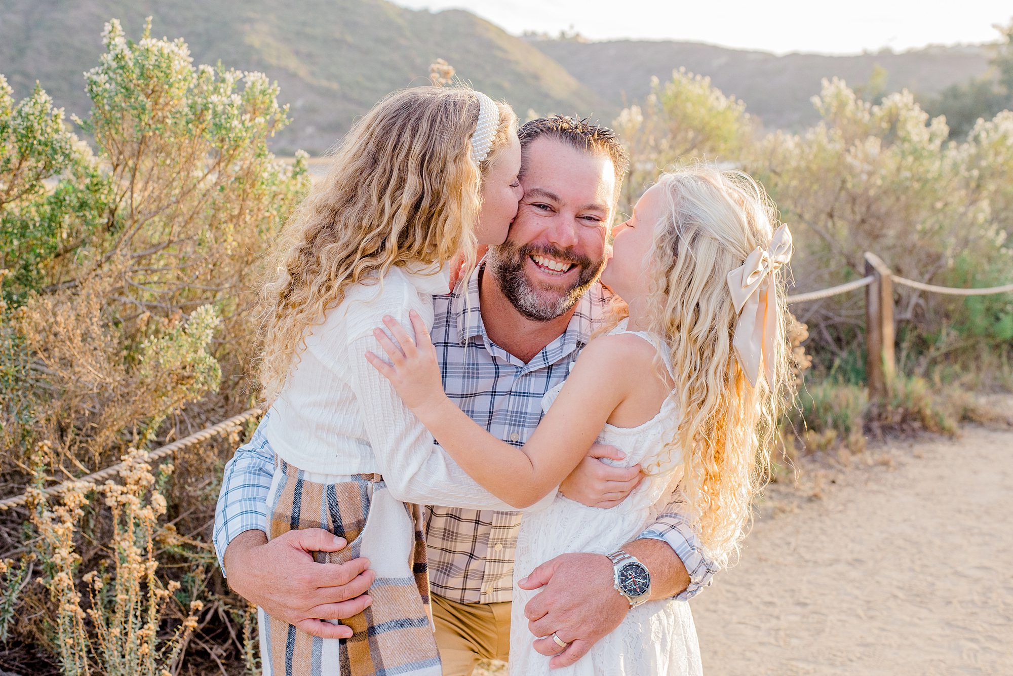 2 little girls kiss their dad's cheek during CA family session