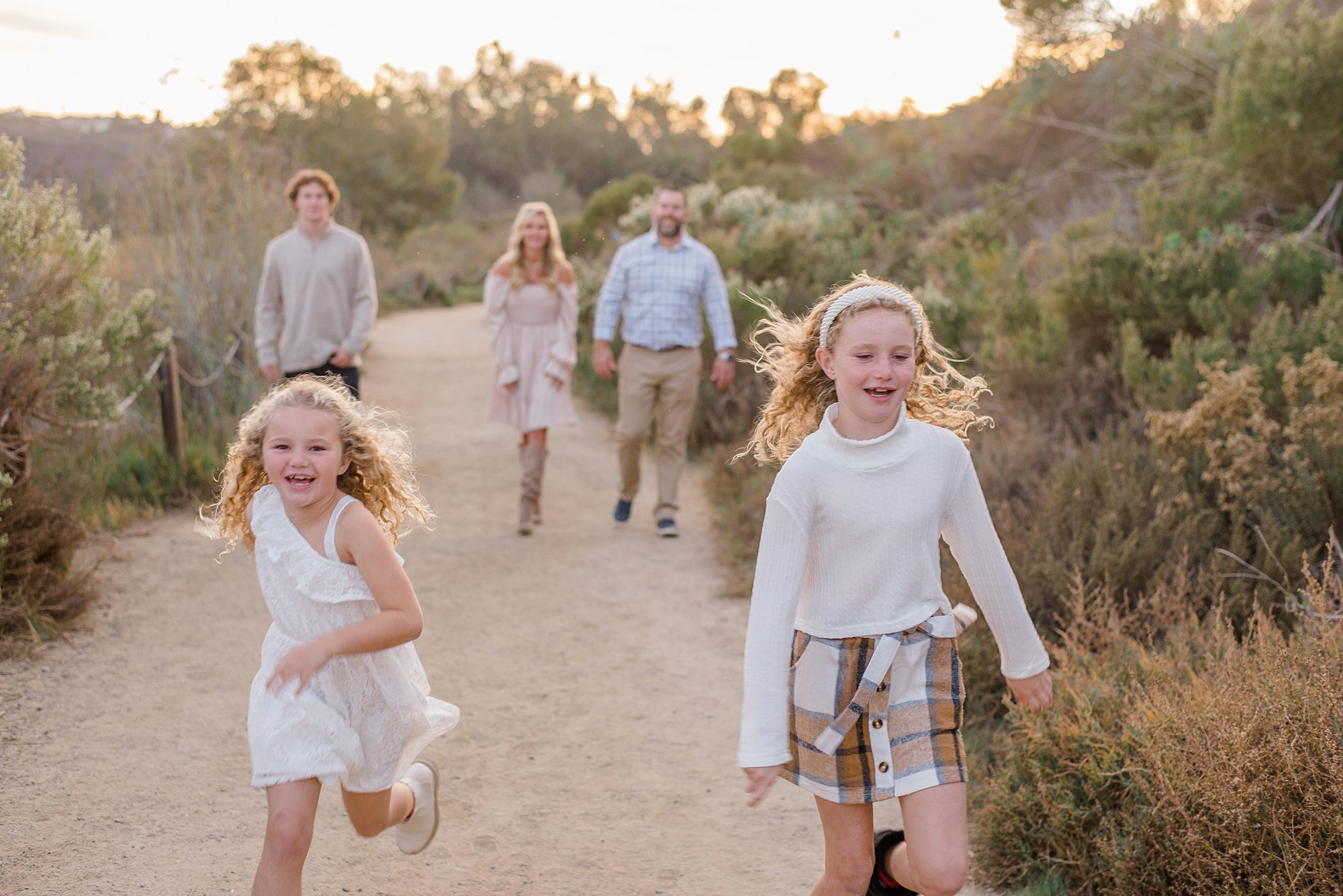 2 girls run ahead of their parents and brother during family session