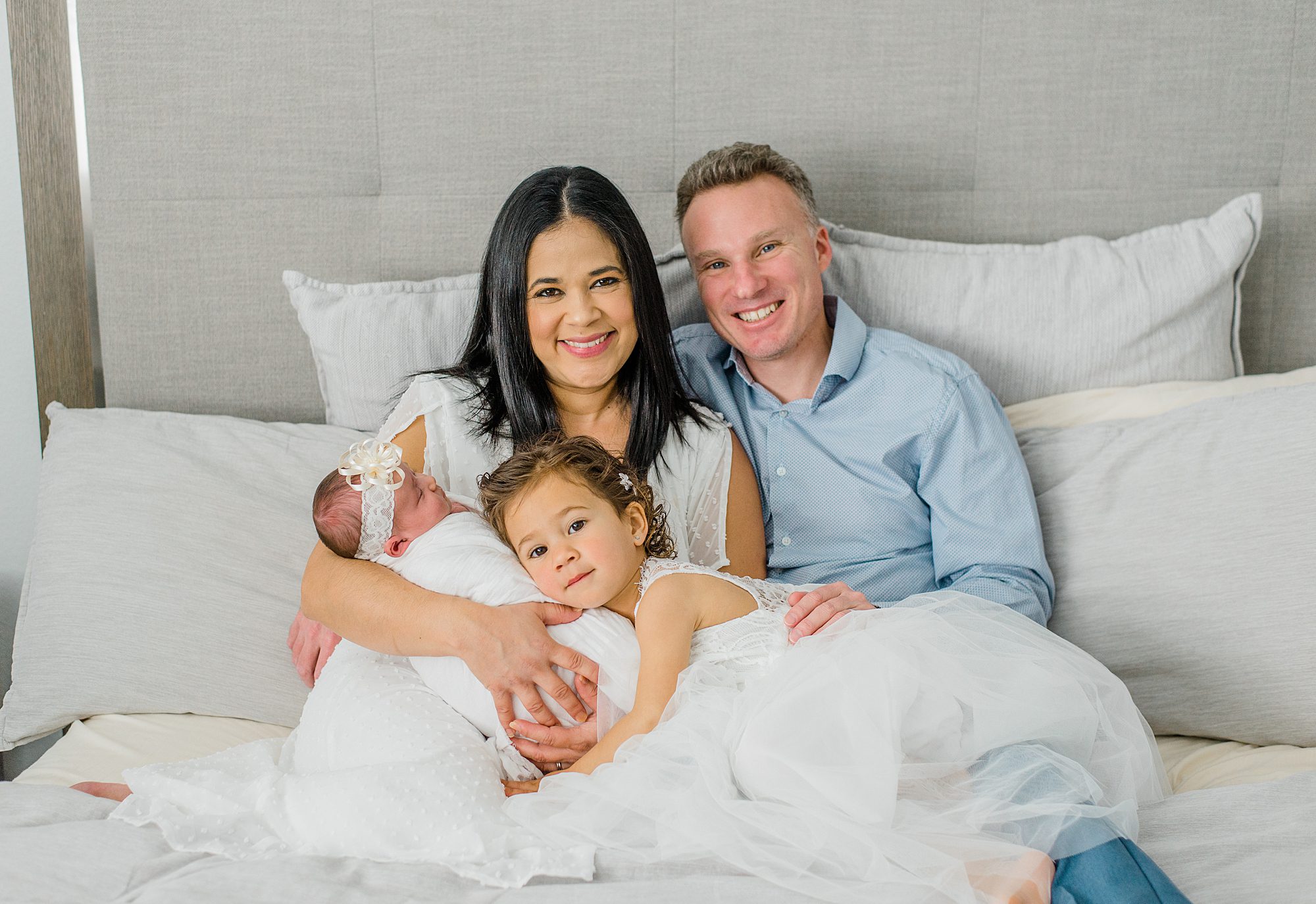 parents hold their two daughters during San Diego In-Home Newborn + family Session