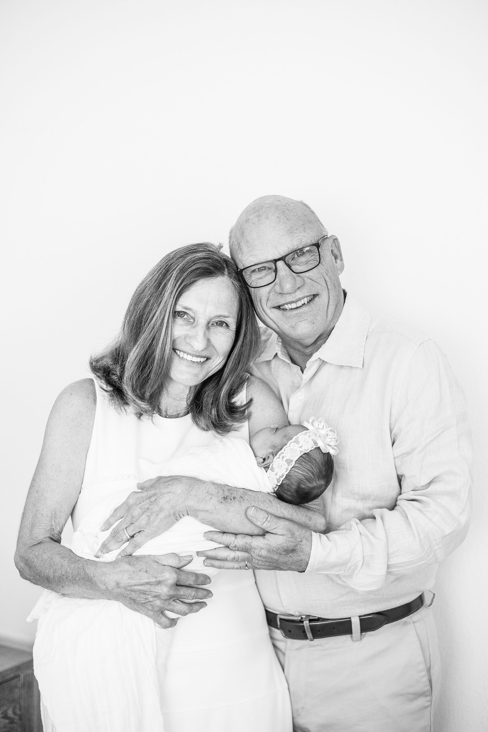 grandparents hold newborn granddaughter 