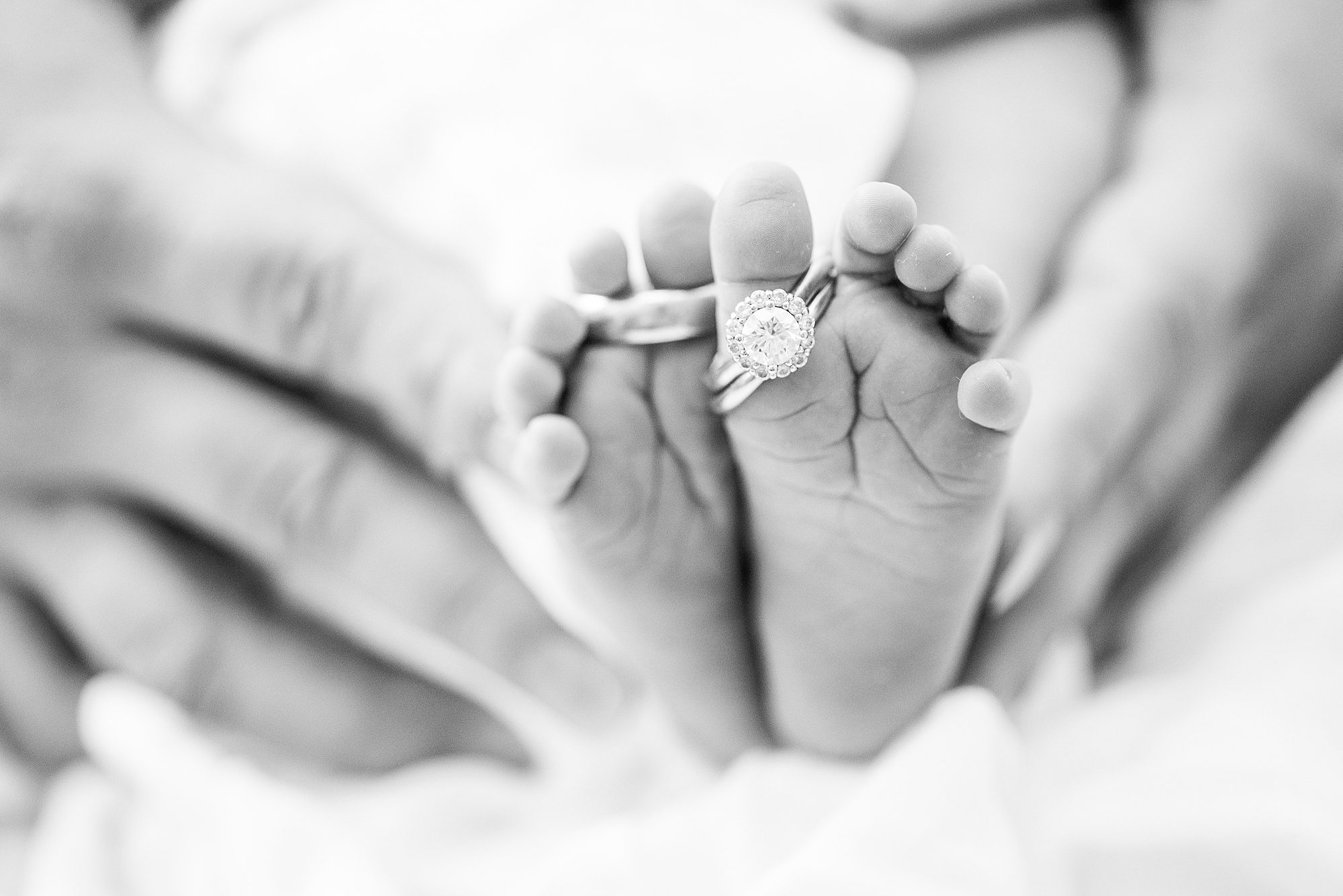 parents wedding rings on newborn toes