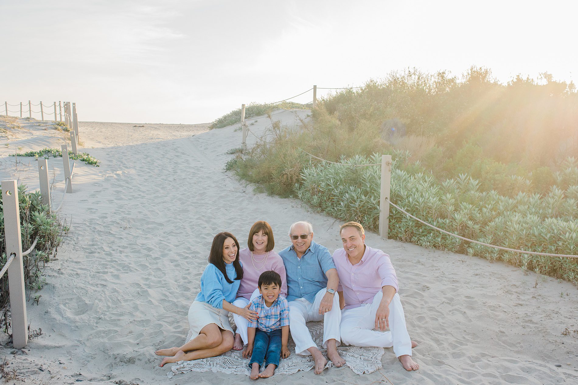family sits in the sand during Coastal Family Portraits in Carlsbad California 
