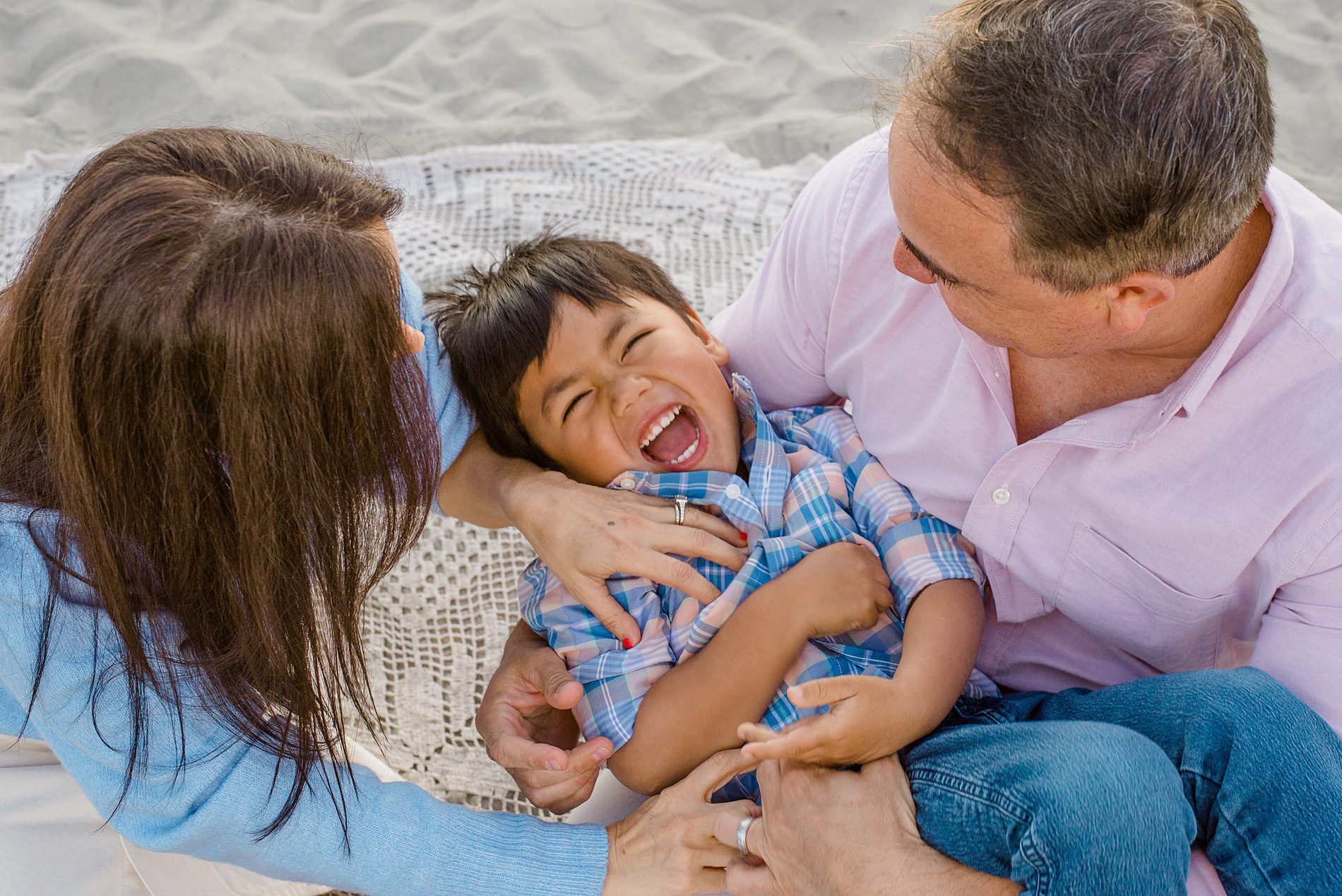 parents tickle their son during Coastal Family Portraits in Carlsbad California 