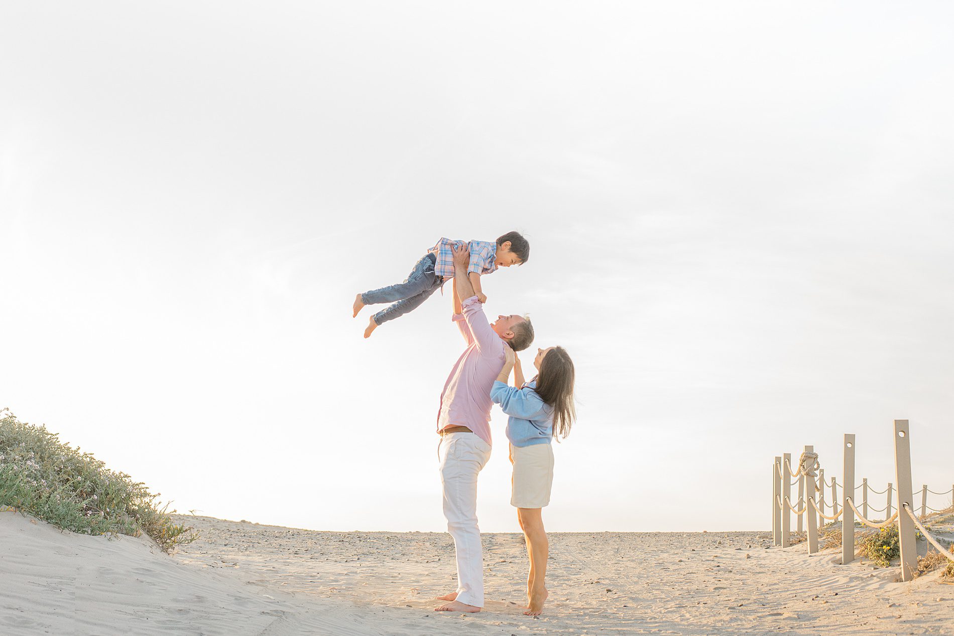 dad holds up son in the air during Coastal Family Portraits in Carlsbad California 