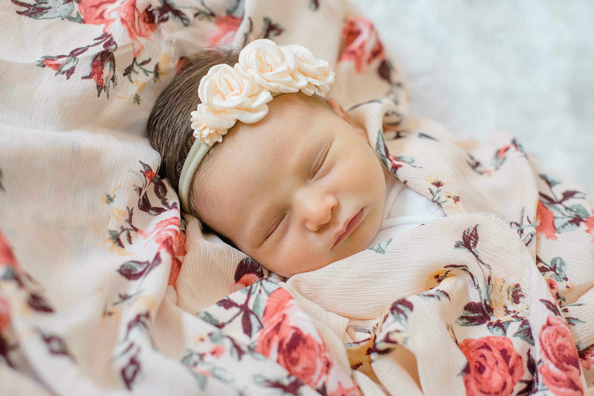 baby girl sleeps wrapped in flower blanket 
