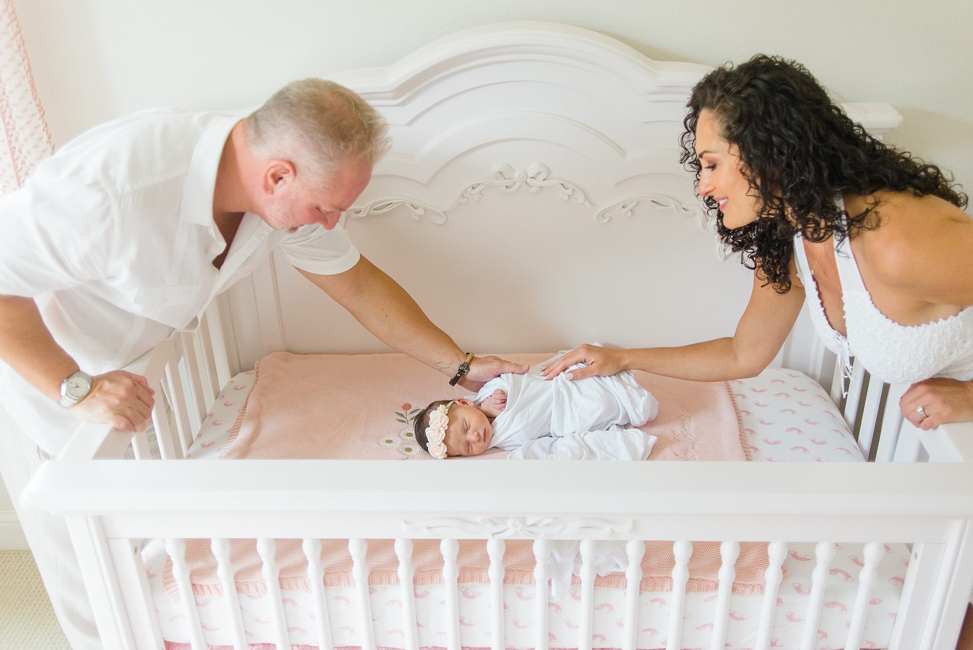 parents watch over their sleeping baby girl