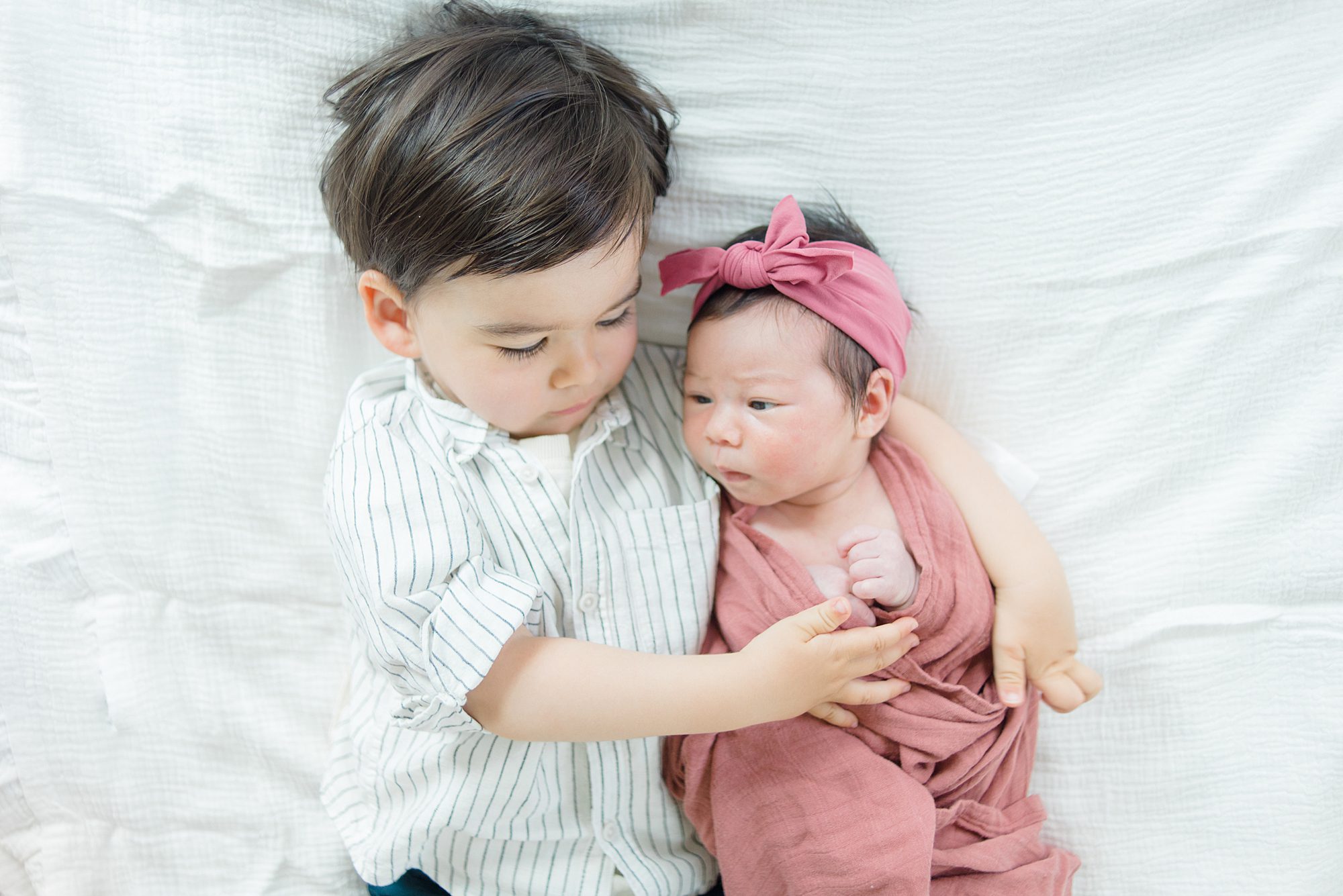big brother holds hugs his little sister during Harmony Grove In-Home Newborn Session 
