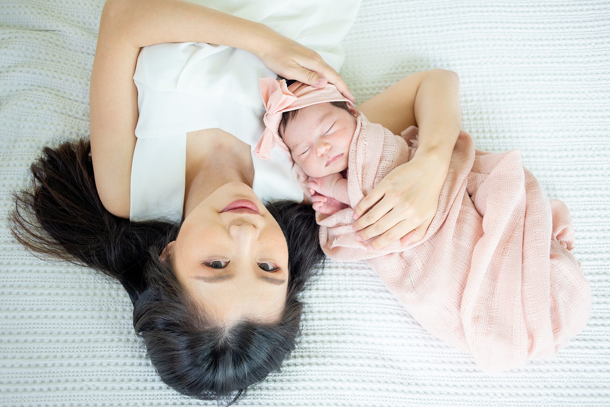 mom and newborn girl wrapped in dusty pink blanket