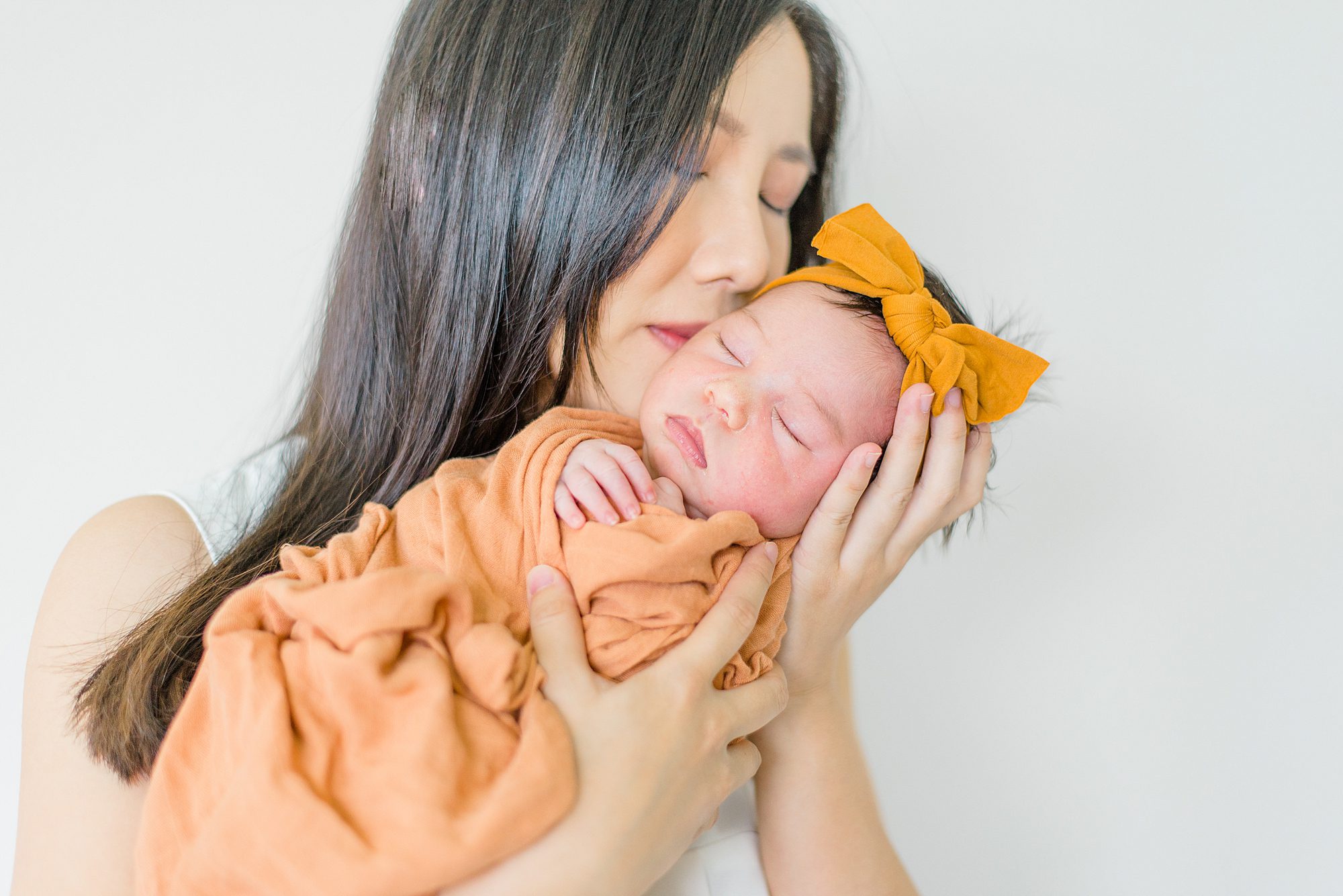 mom kisses newborn daughter 