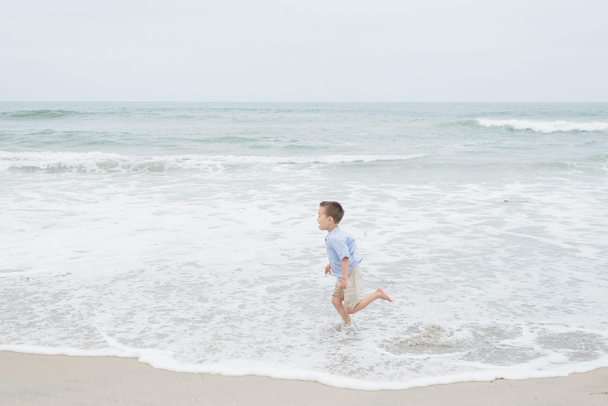 little boy runs through the ocean during San Diego Family Beach Session