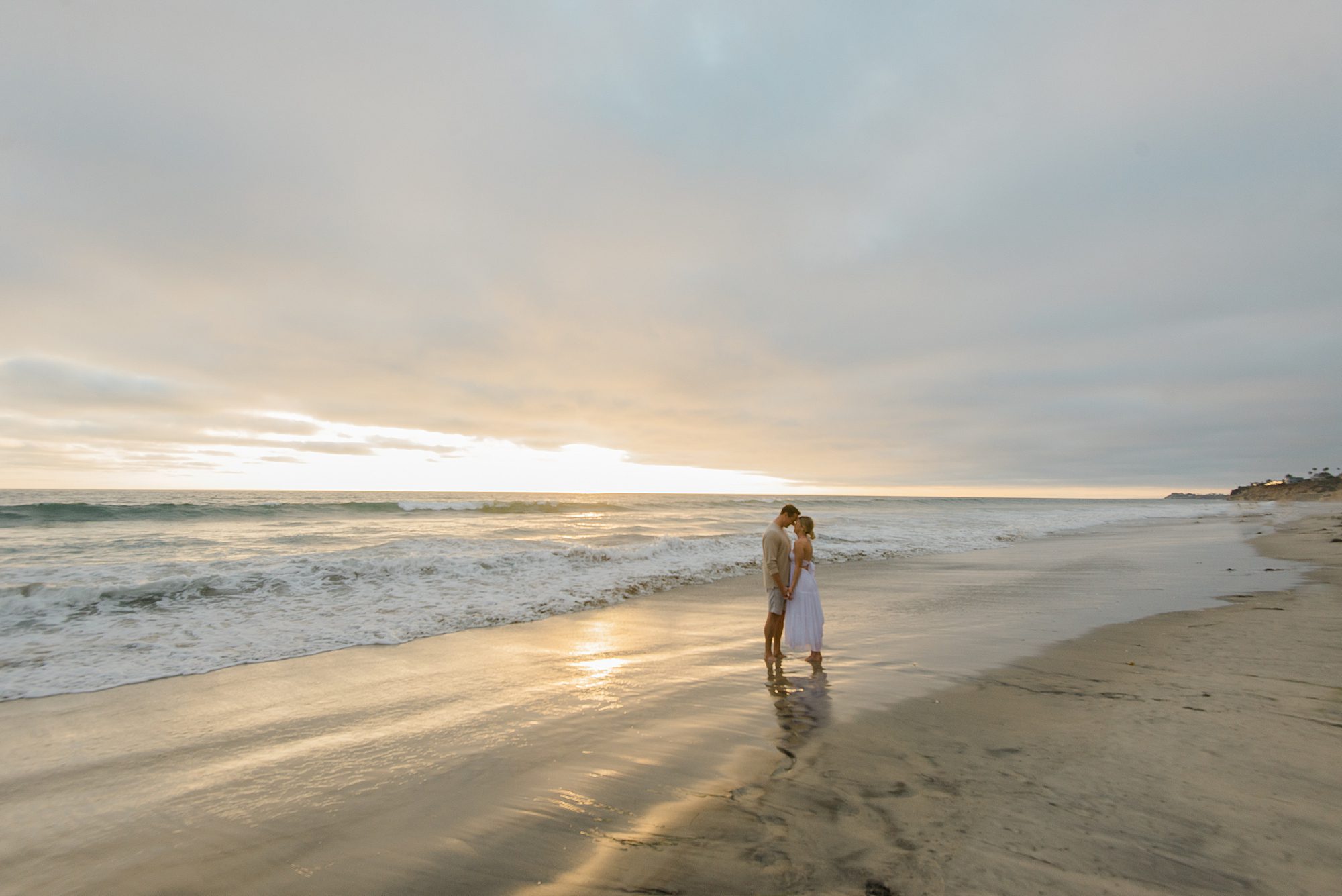 couple kiss at the beach during Gorgeous Family Beach Session in San Diego