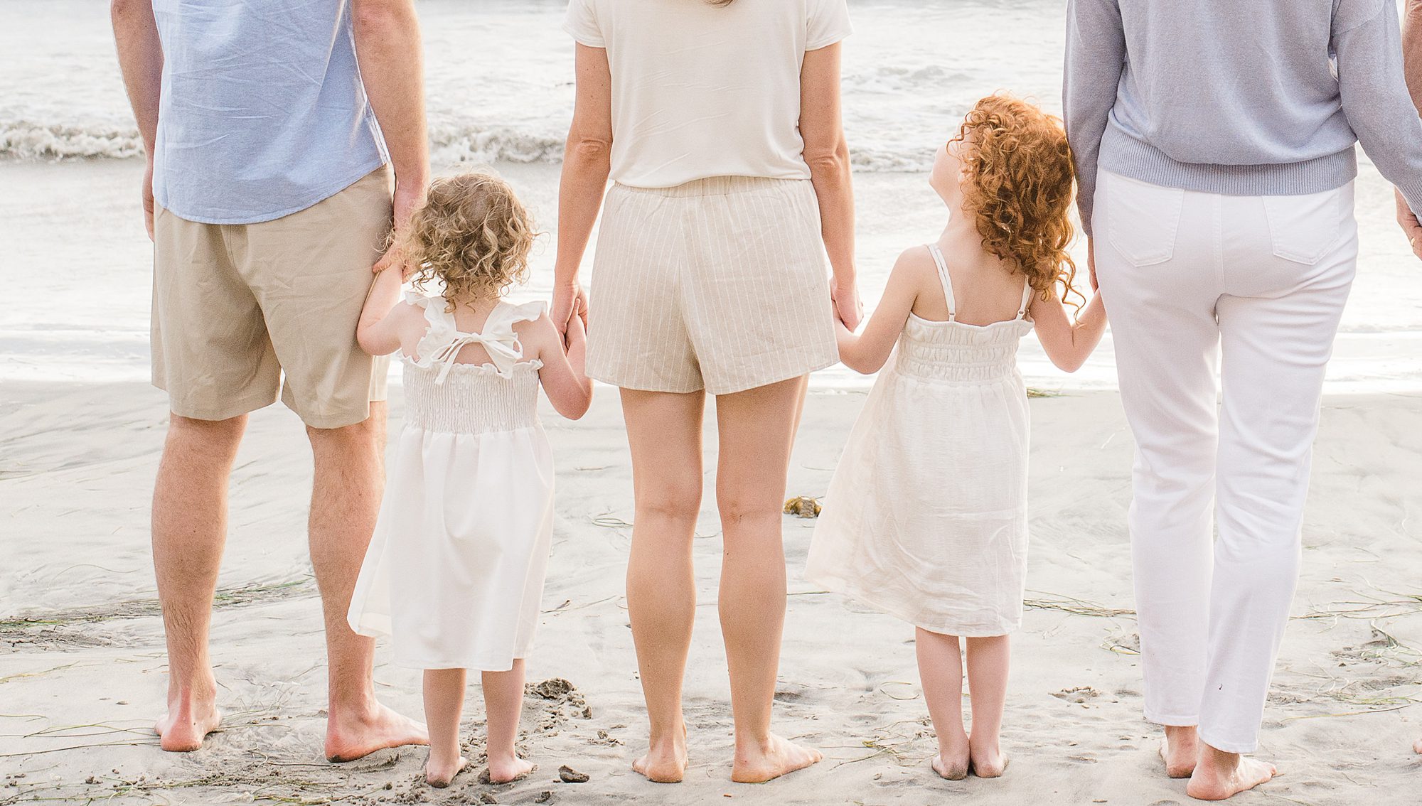 family hold hands as they walk towards ocean