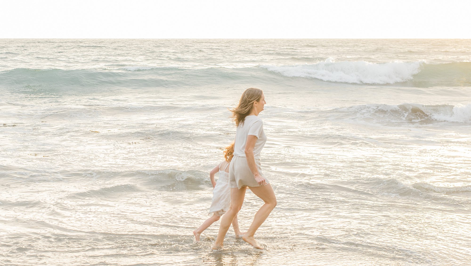 mother and daughter run along the beach