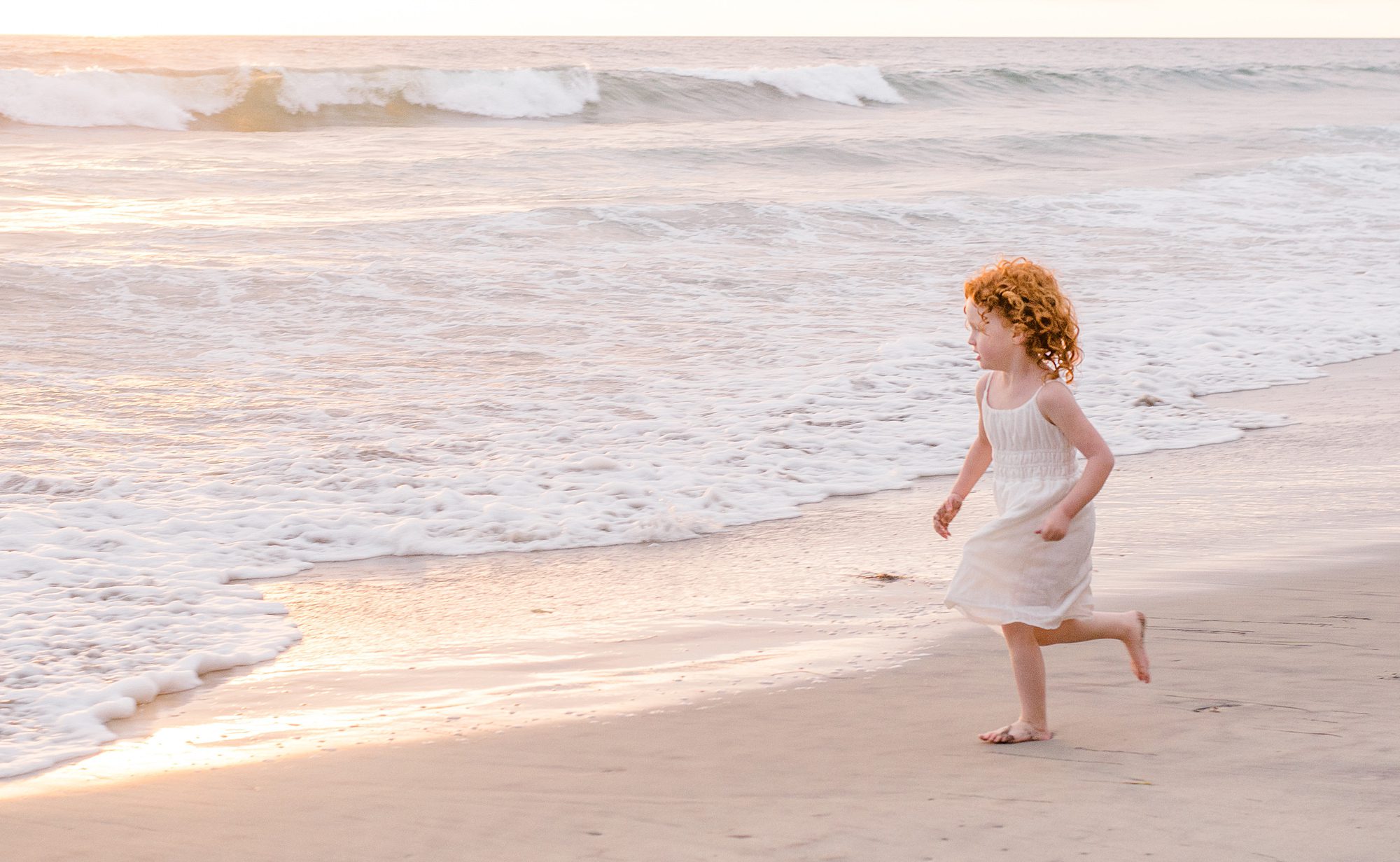 little girl runs along the beach in San Diego