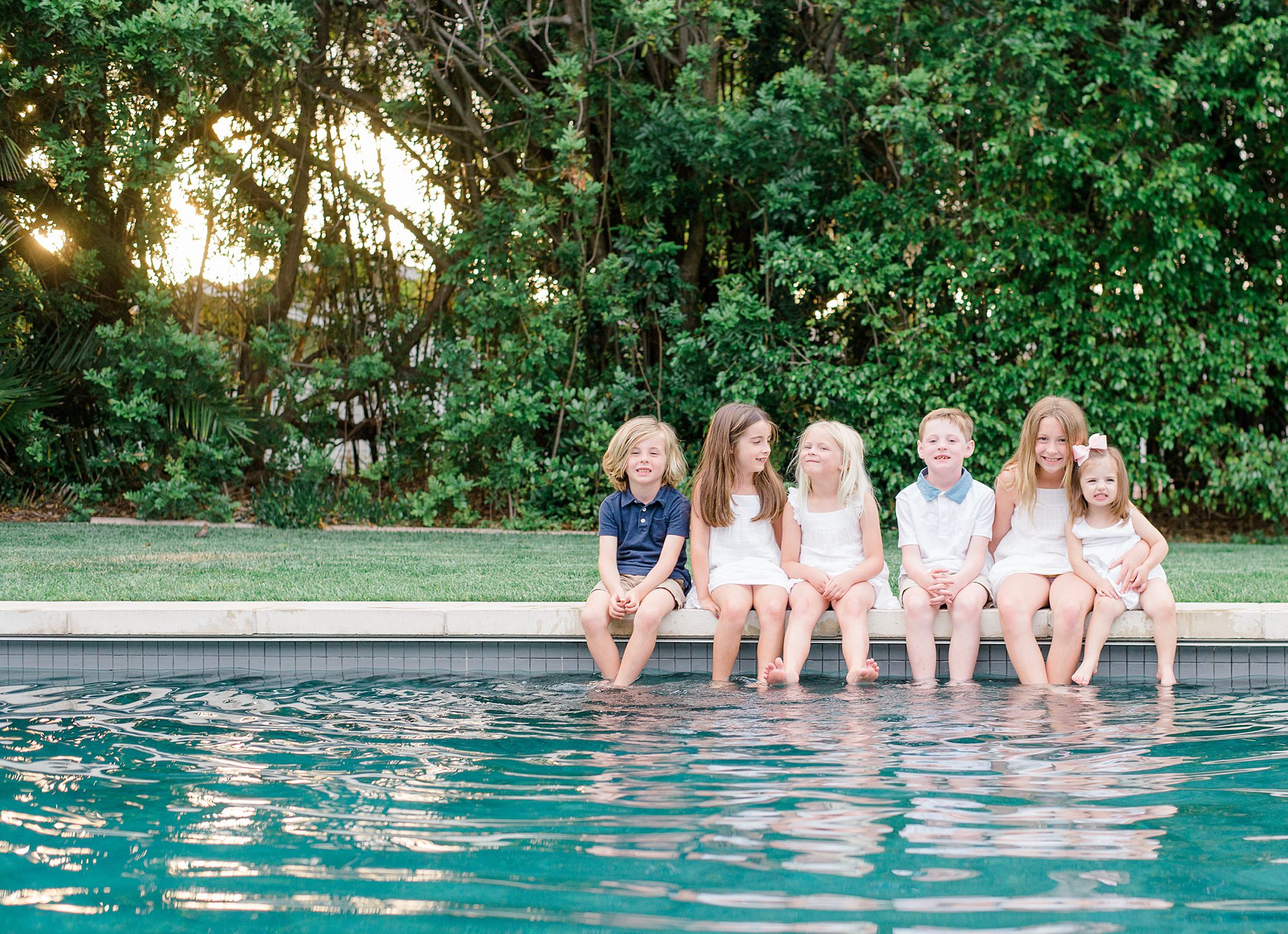 children sit on edge of pool in CA 
