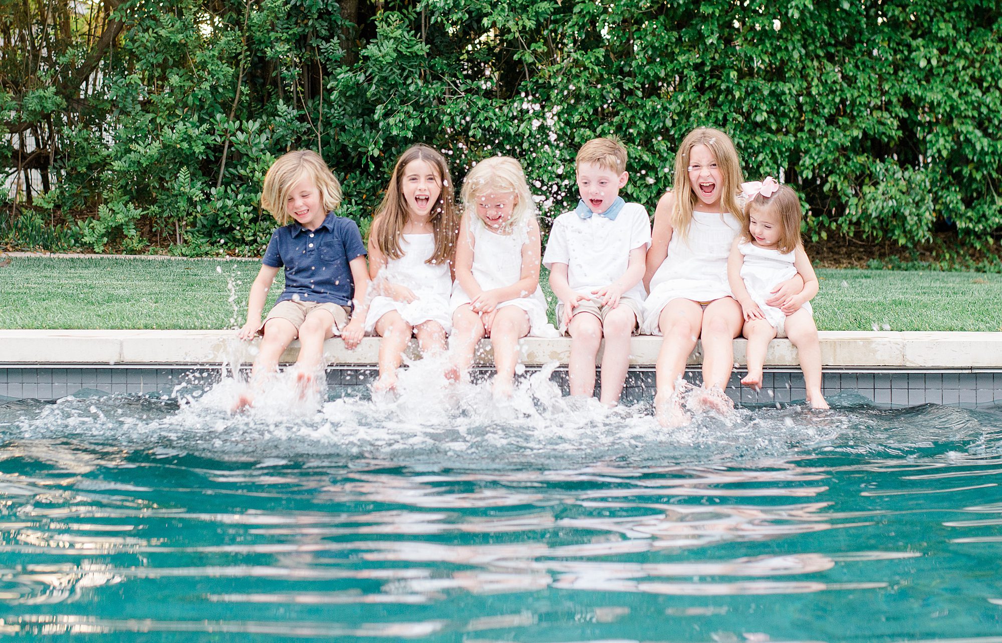 cousins put their feet in the water of pool during Summer Extended Family Session in Rancho Santa Fe, California 