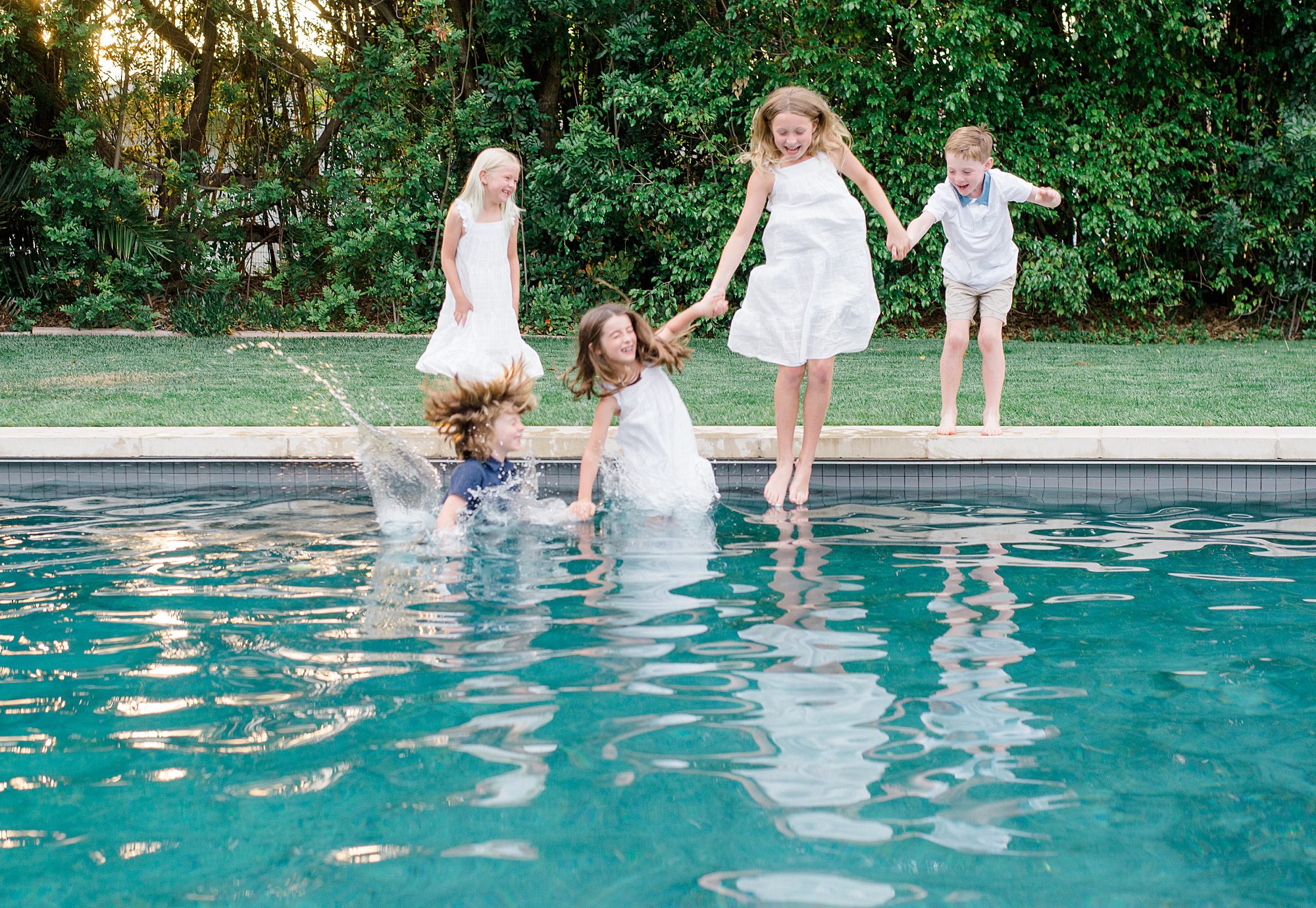 cousins jump in pool during summer family session 