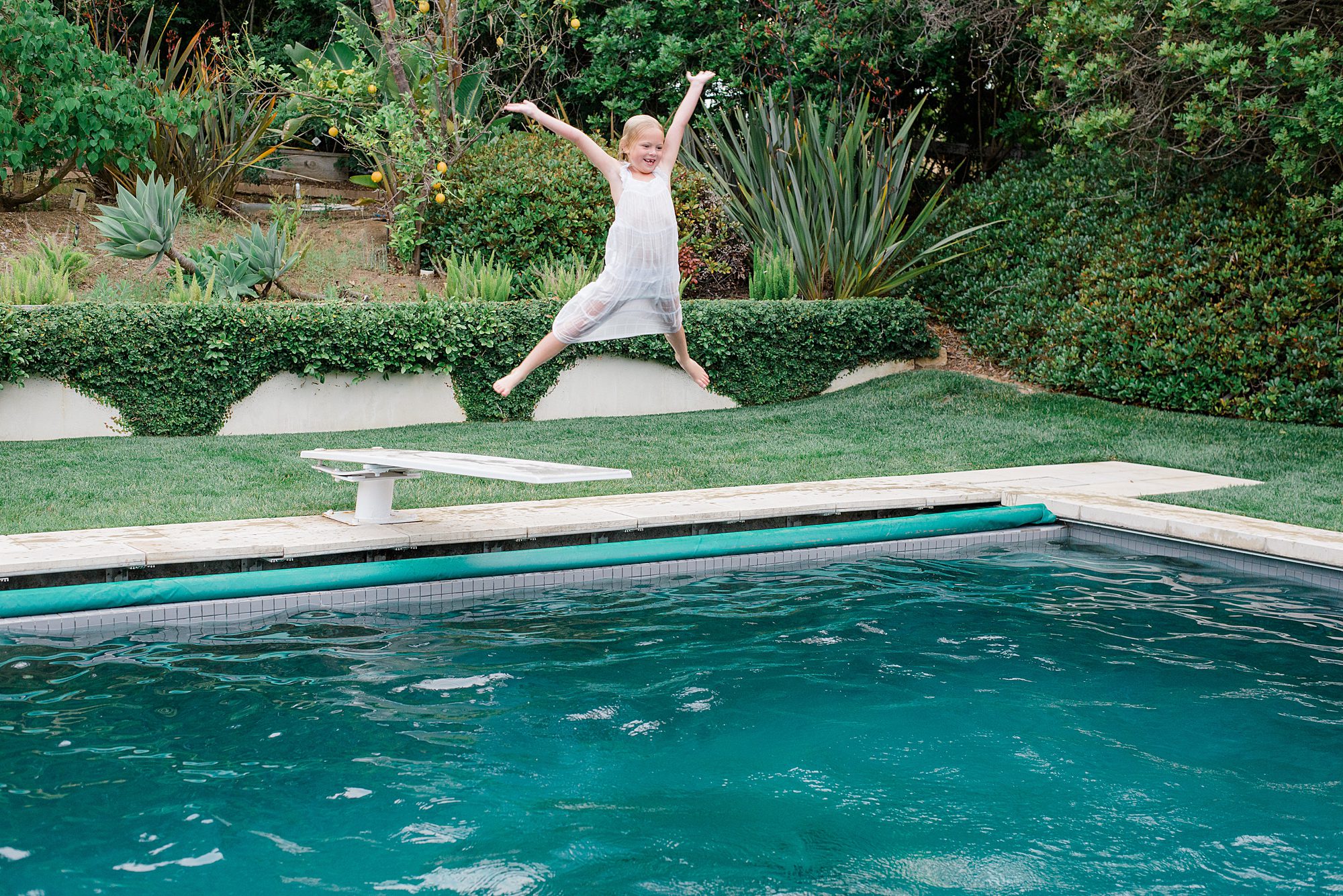 little girl jumps off diving board during Summer Extended Family Session in Rancho Santa Fe, California