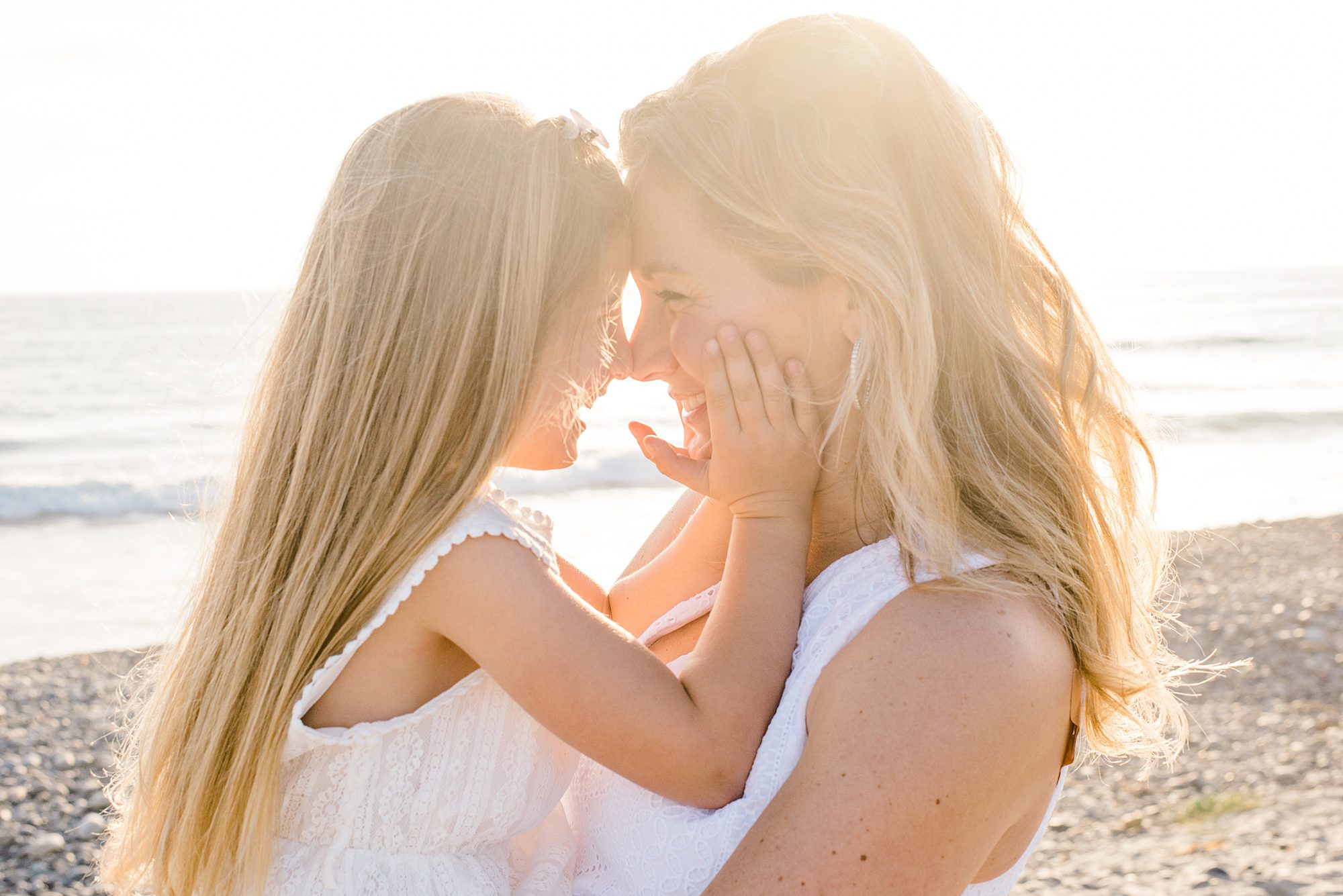 mom holds little girl in arms during California Coastline Beach Session in Carlsbad, CA 