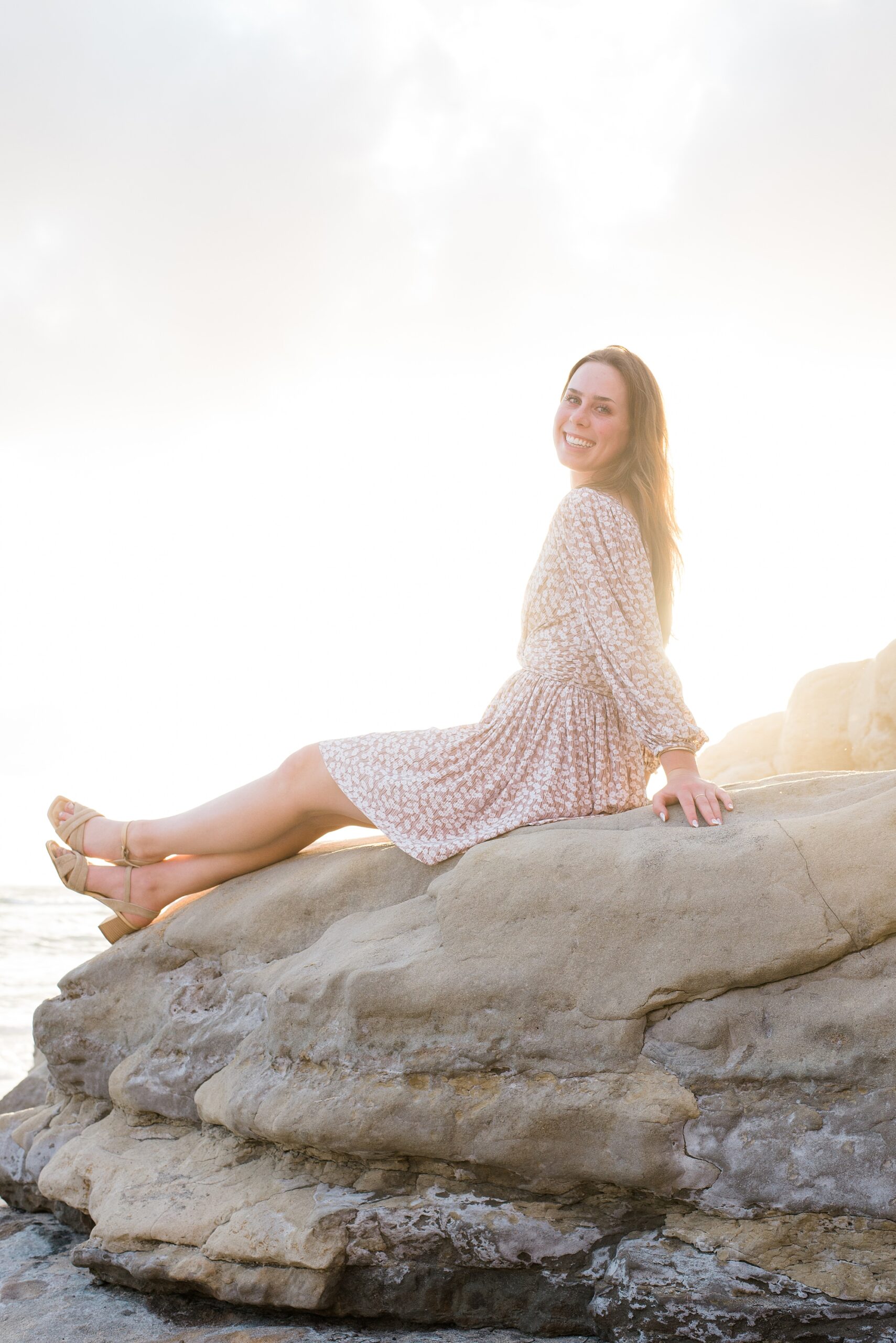 senior girl sits on cliffs in carlsbad CA