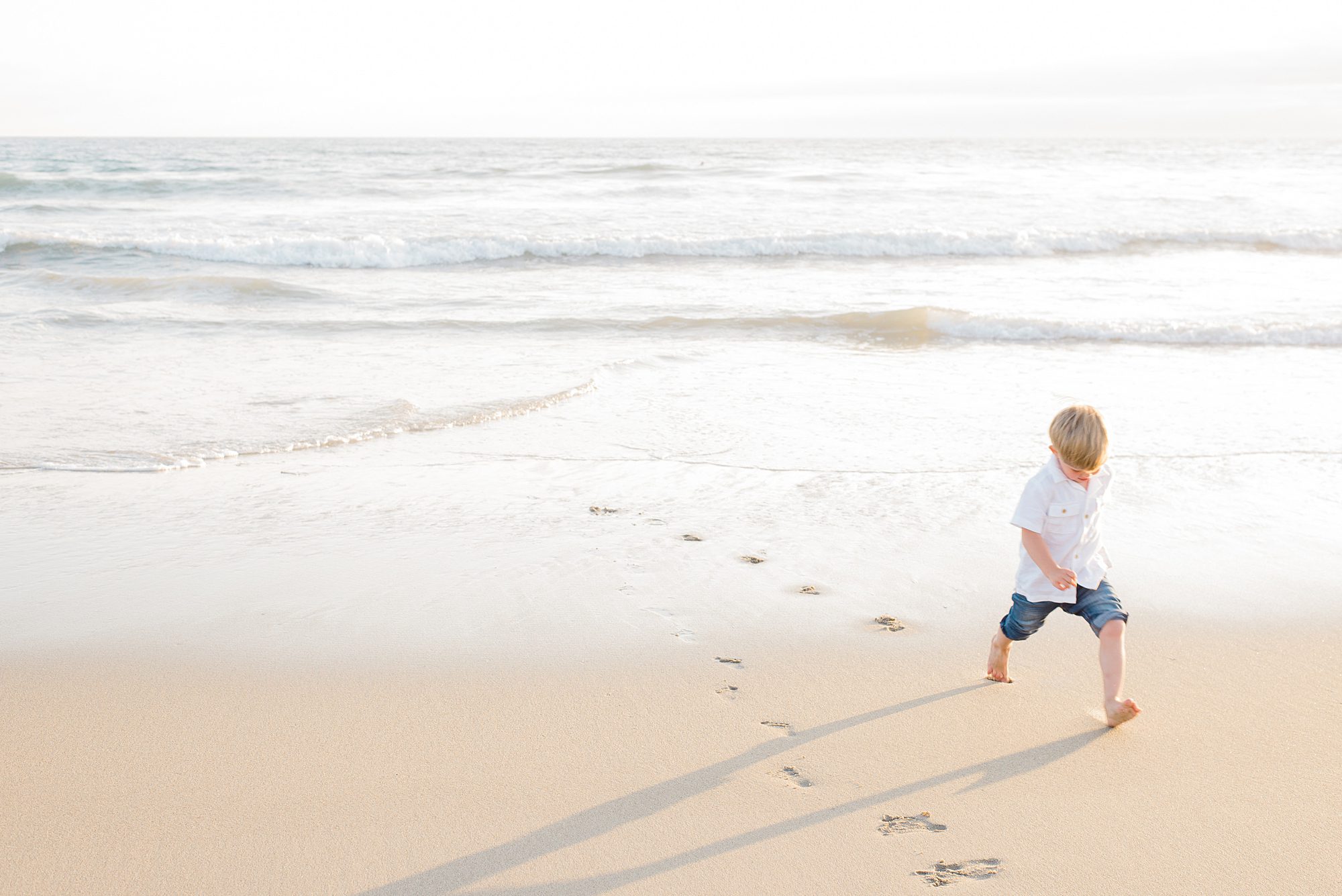 little boy runs along the sand in CA