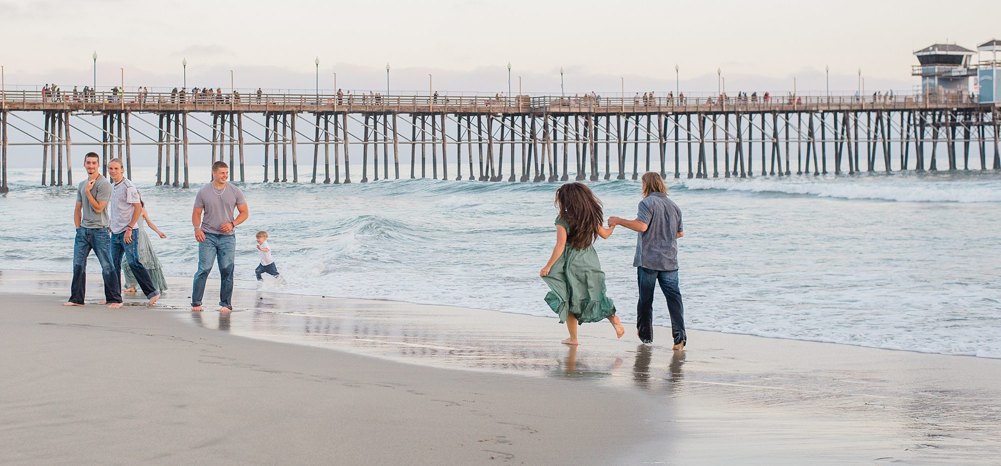 family runs into the ocean at Oceanside California 