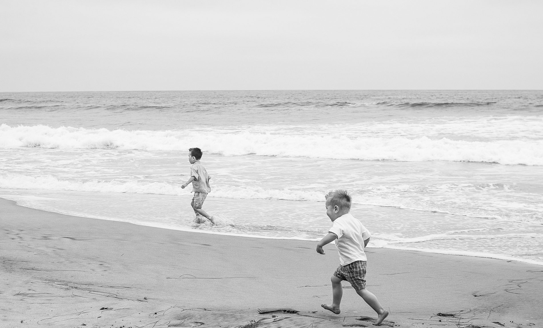 brothers run through the waves of ocean from San Diego Family Beach Session