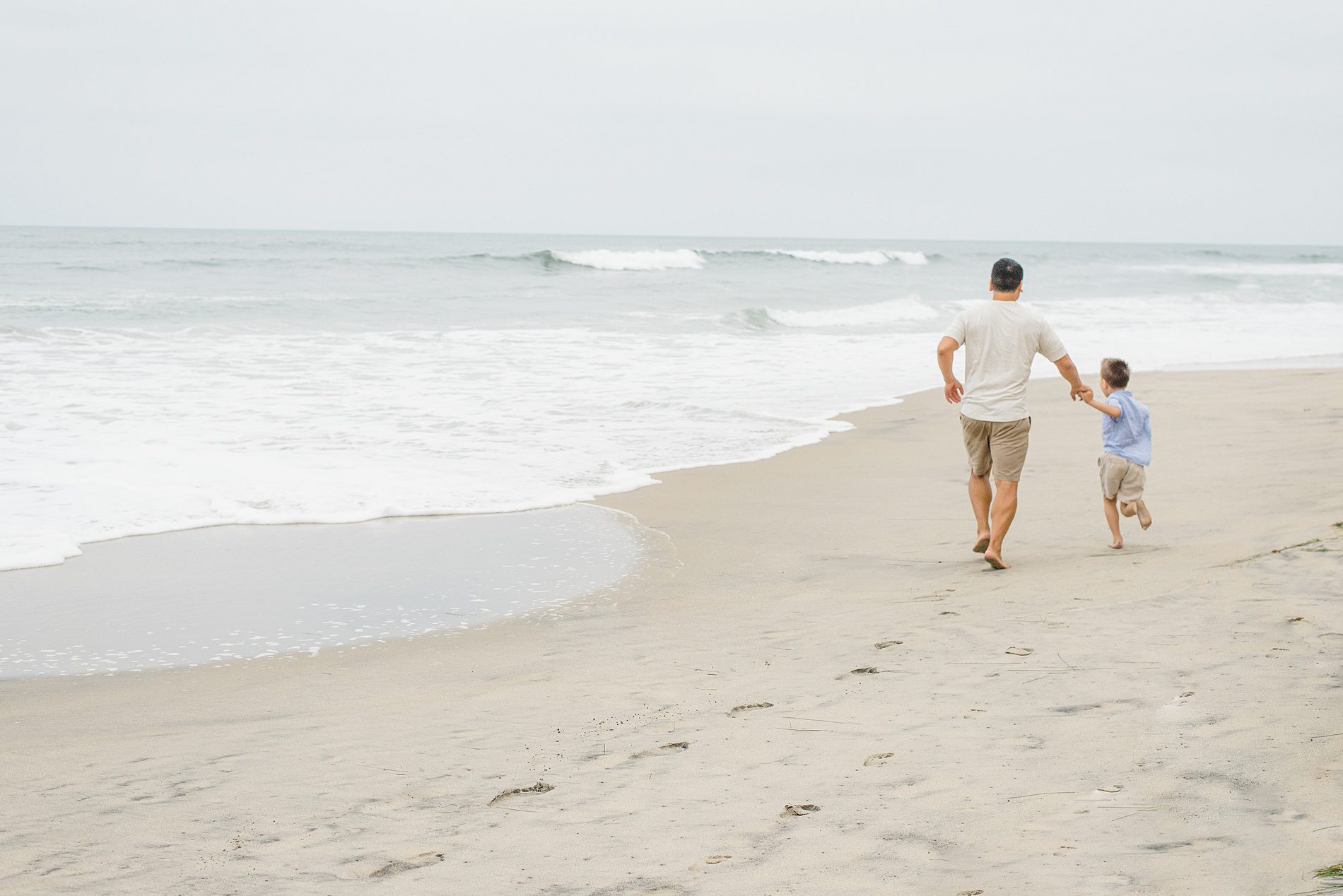 dad and son walk down the beach together 
