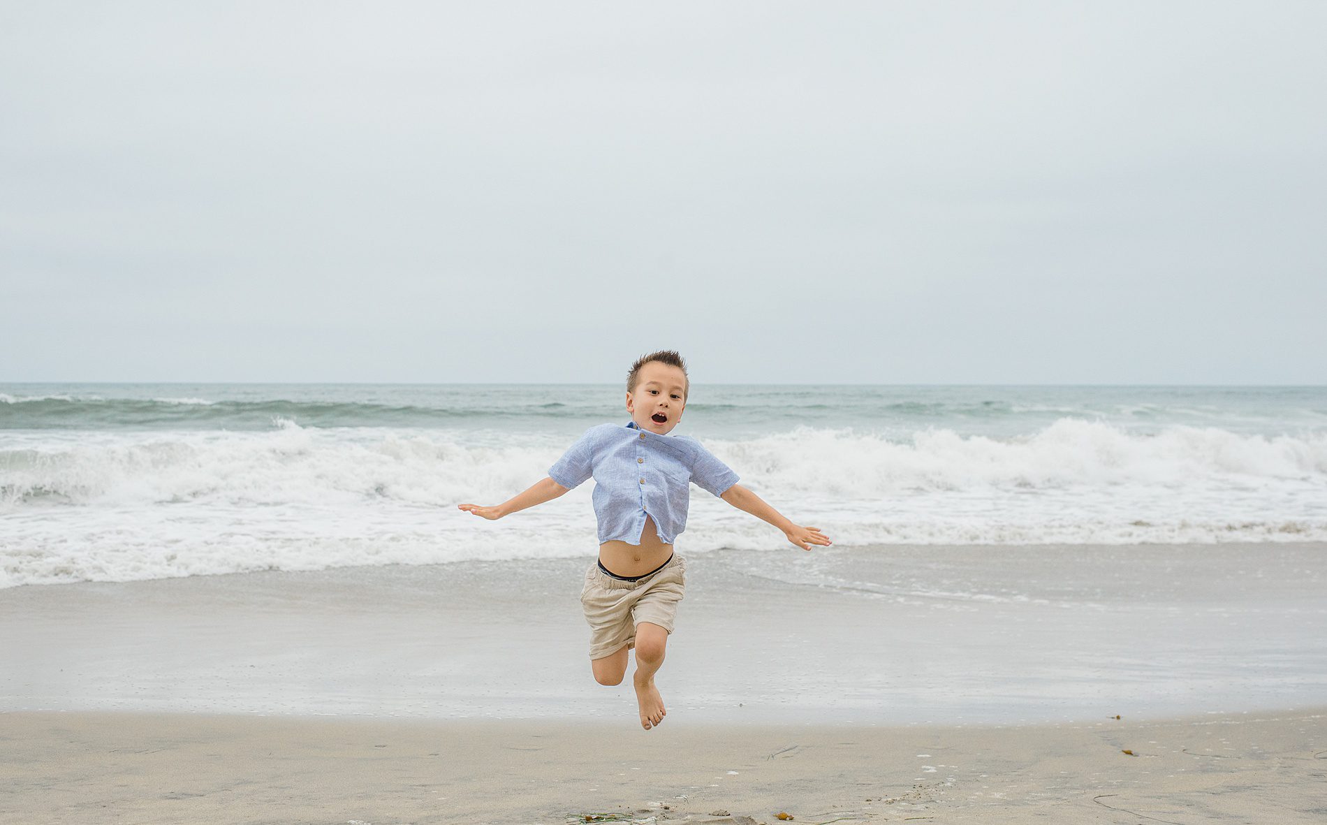 little boy runs around at San Diego beach during family session
