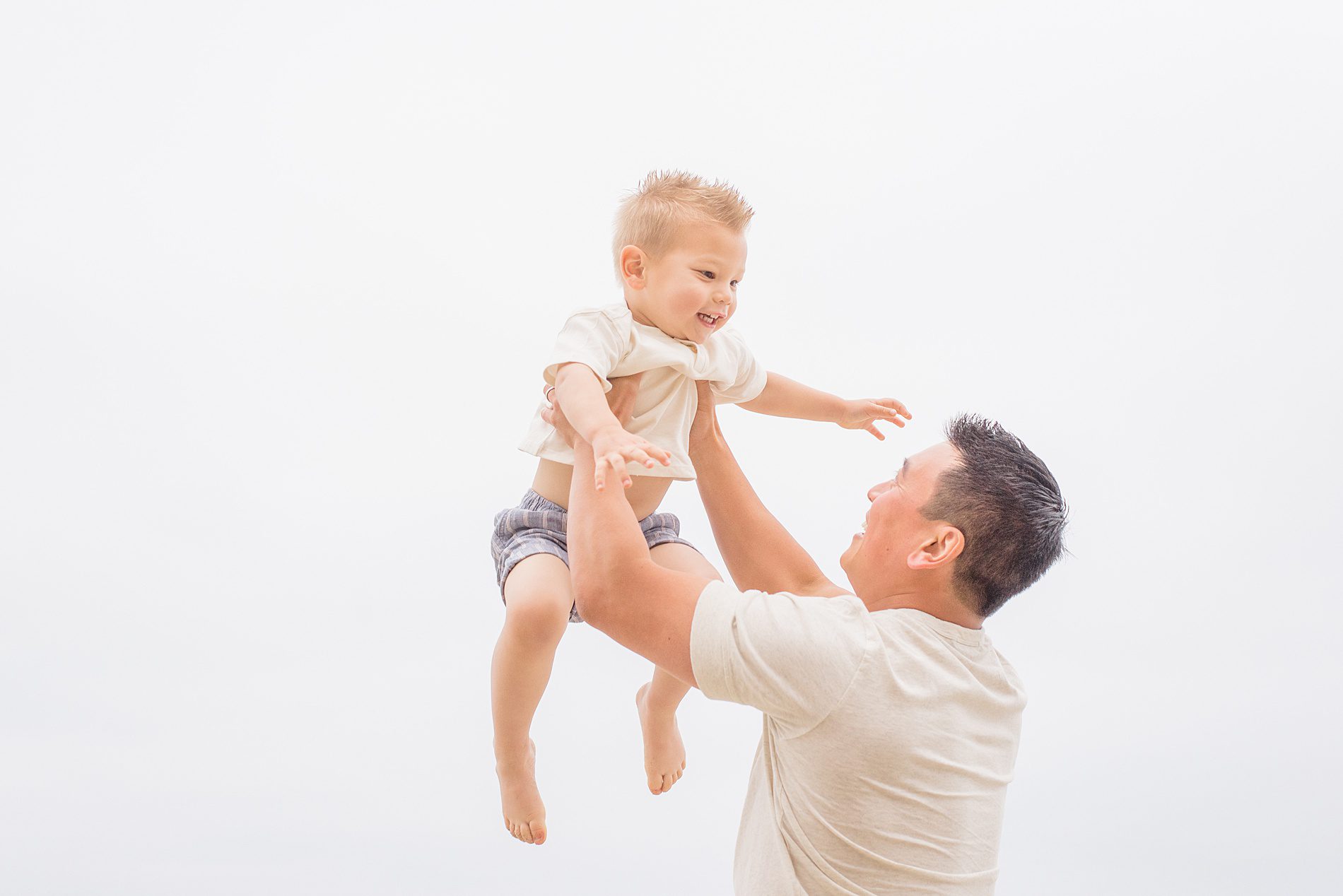 dad holds his son up in the air during candid family portraits