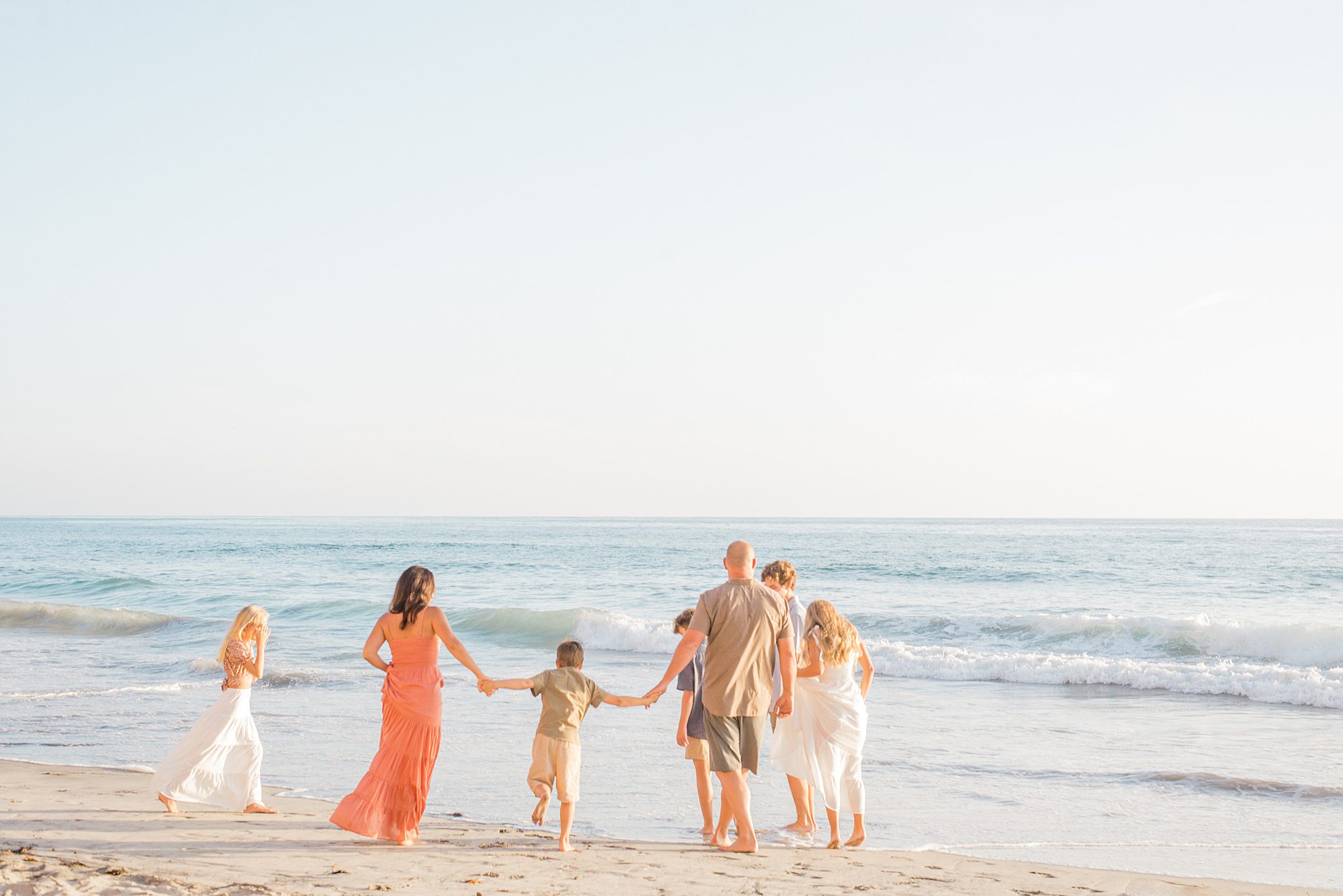 family of seven walks together on the beach