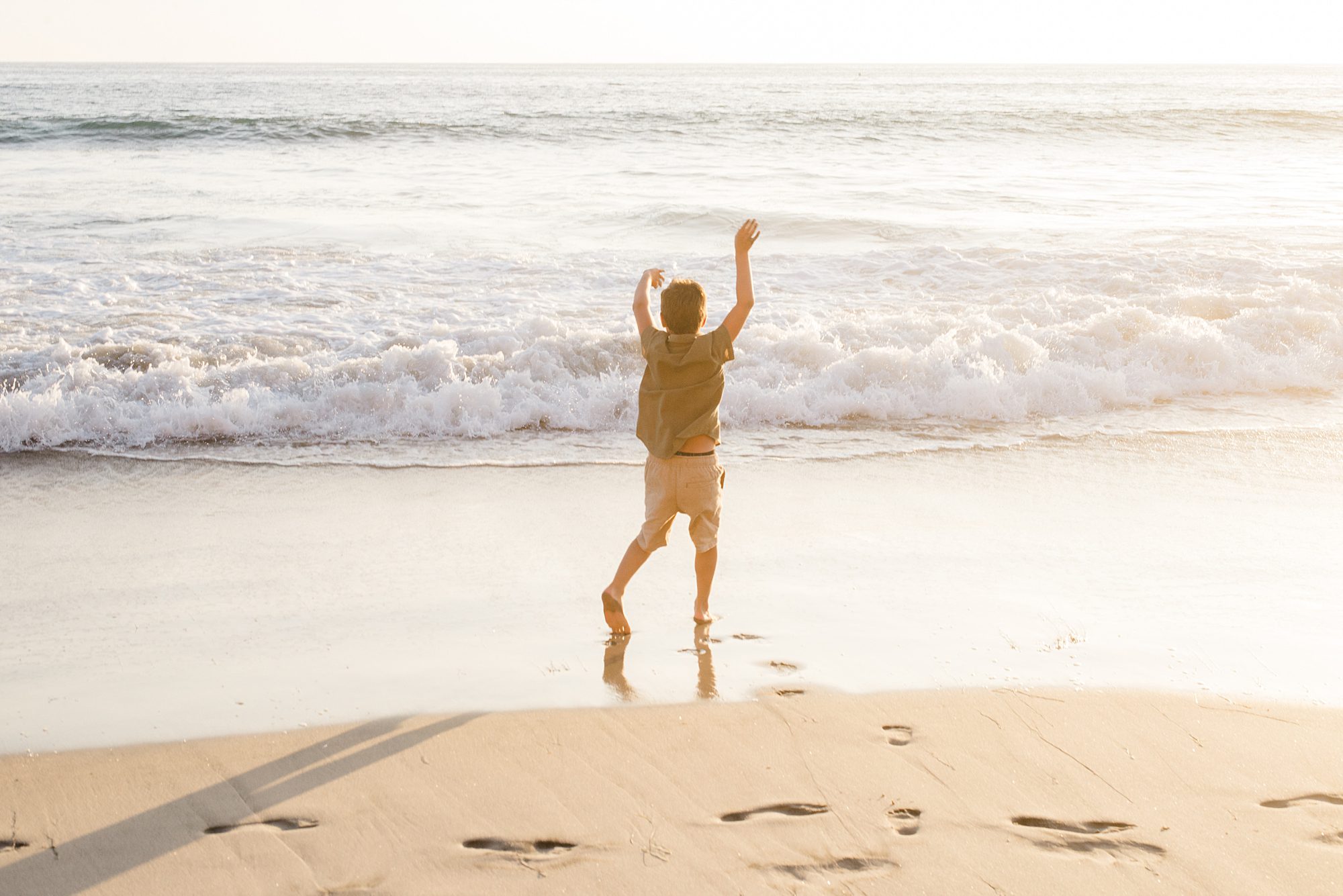 boy runs into ocean waves during Solana Beach Family Session