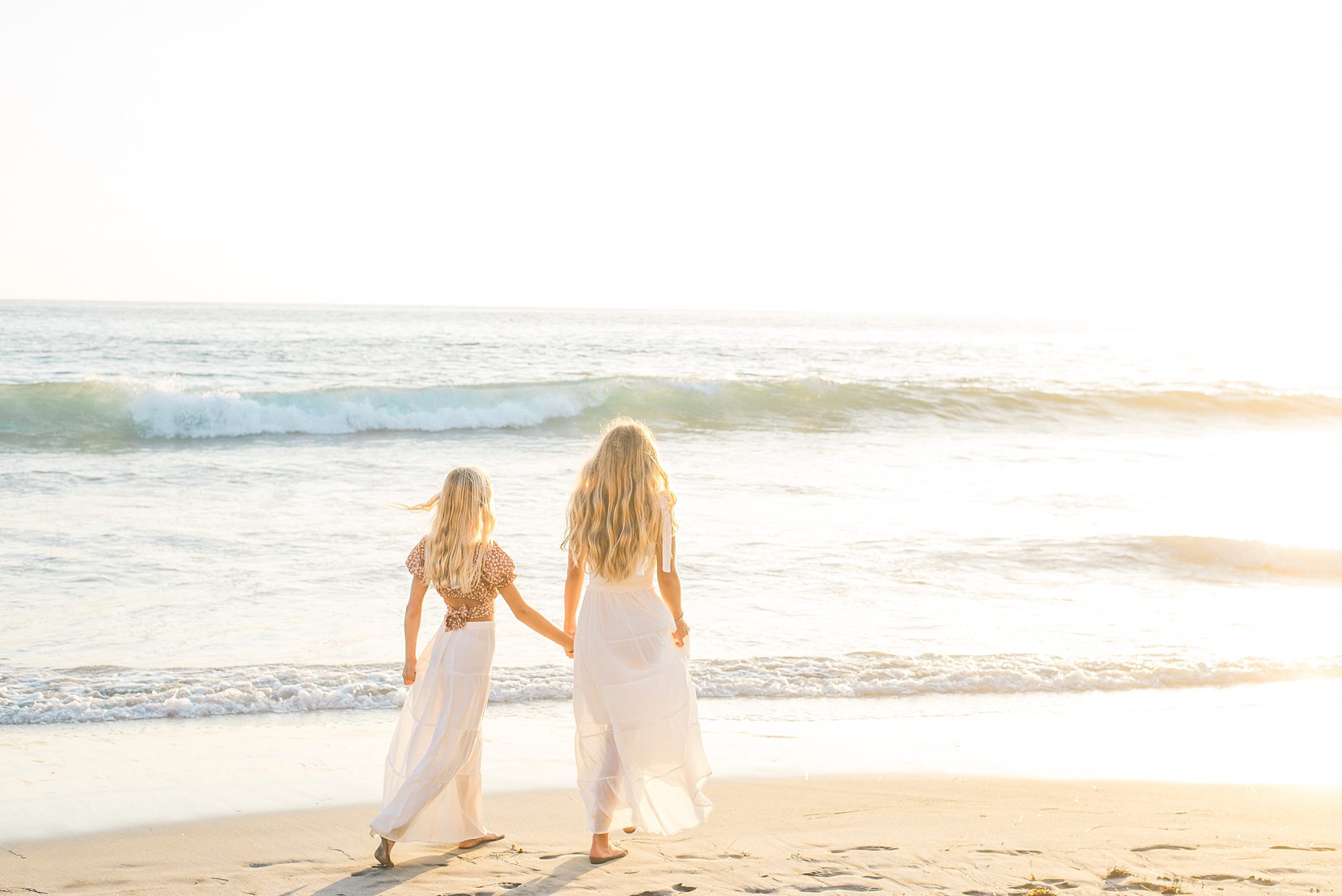 sisters walk together on the beach during Solana Beach Family Session