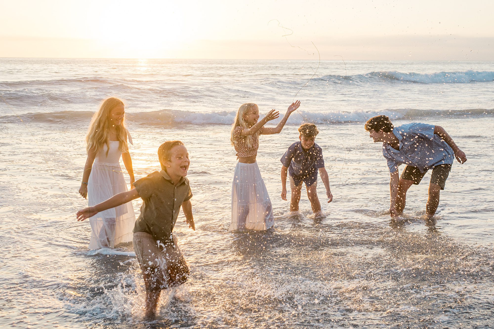 family splashes together in the ocean water at Solana Beach