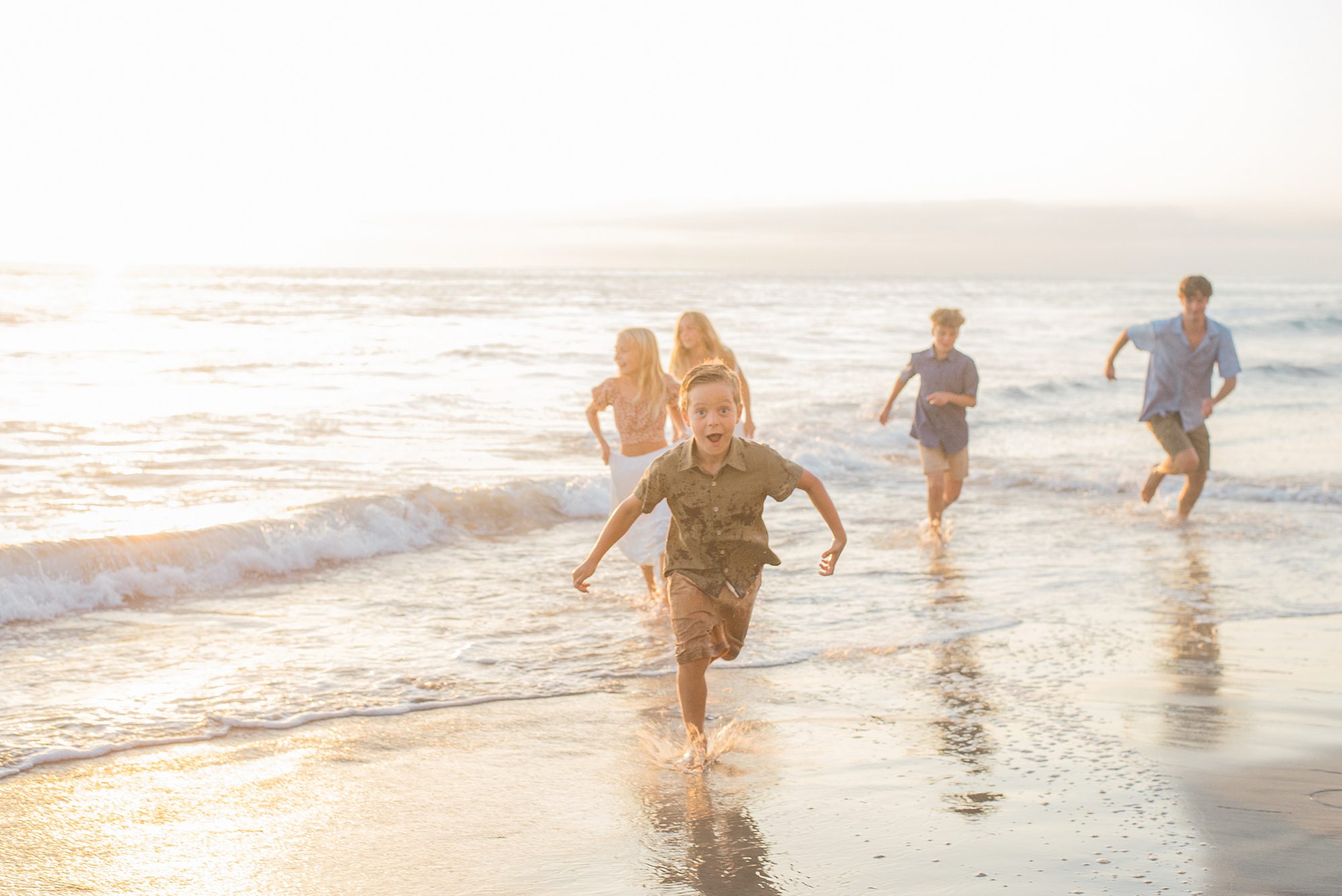 children splash in the ocean during Solana Beach Family Session