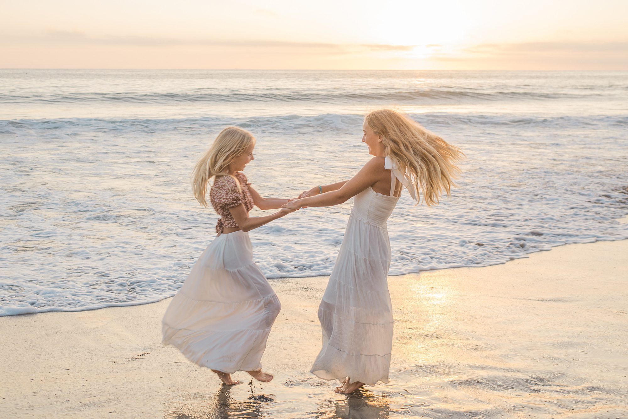sisters dance on the beach in CA during family photos 