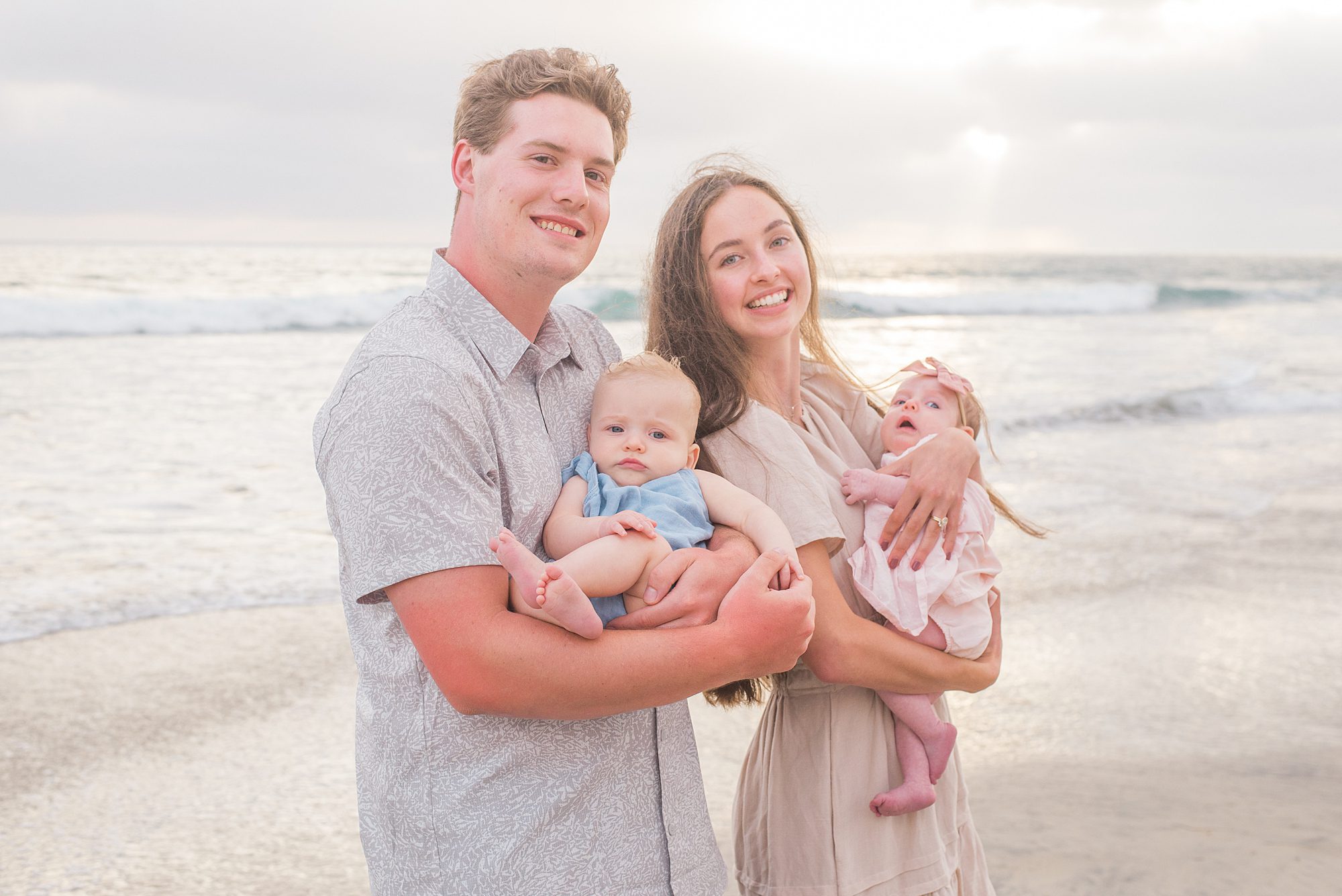 couple hold their niece and nephew from Extended Family Sunset Session in Oceanside, CA 