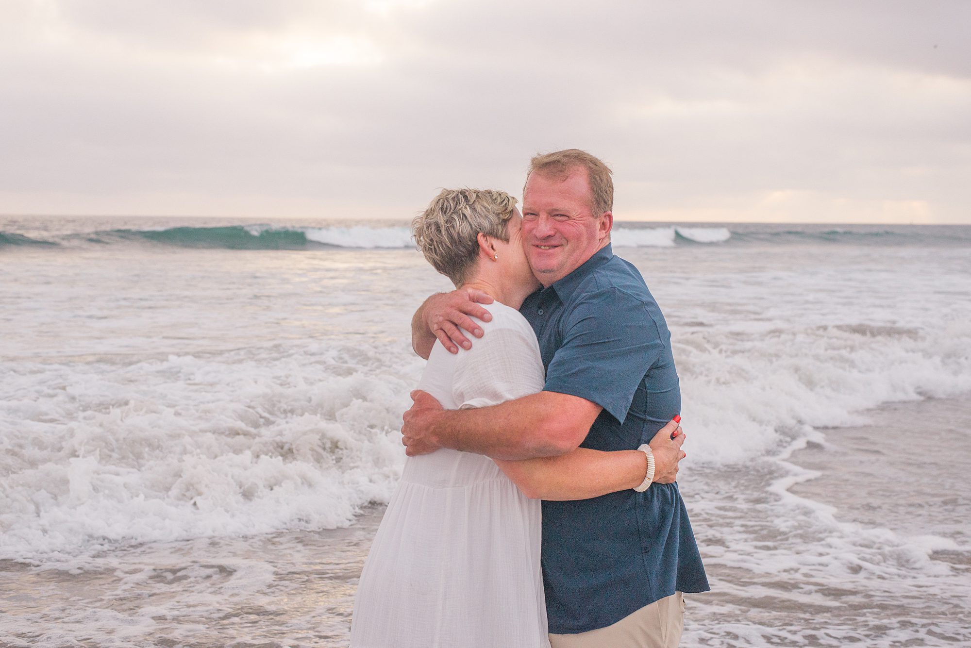 husband hugs his wife on the beach