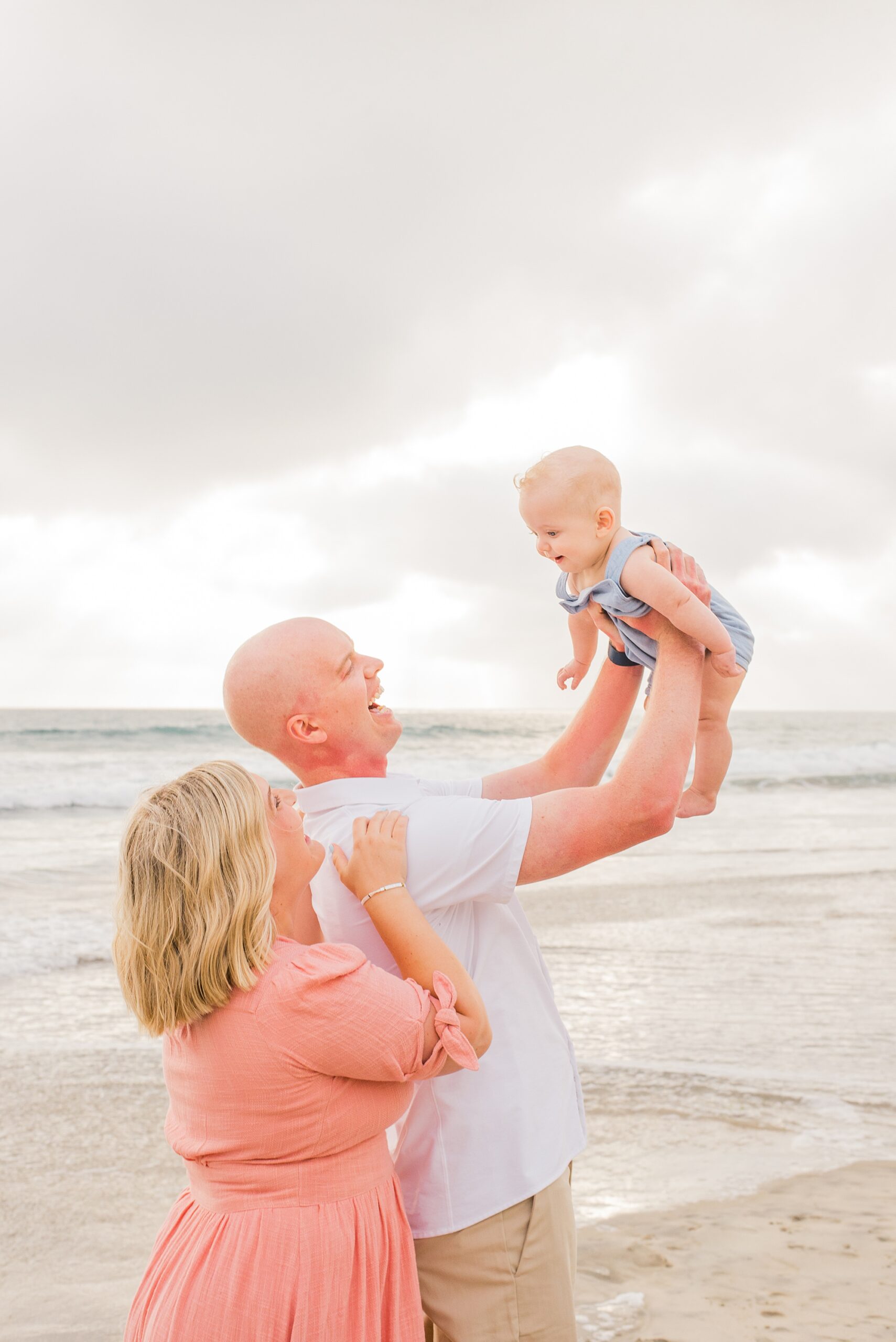 parents lift baby up at the beach 