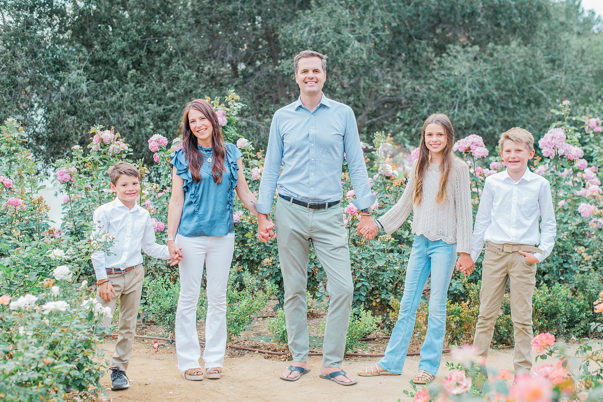 family of five hold hands in garden