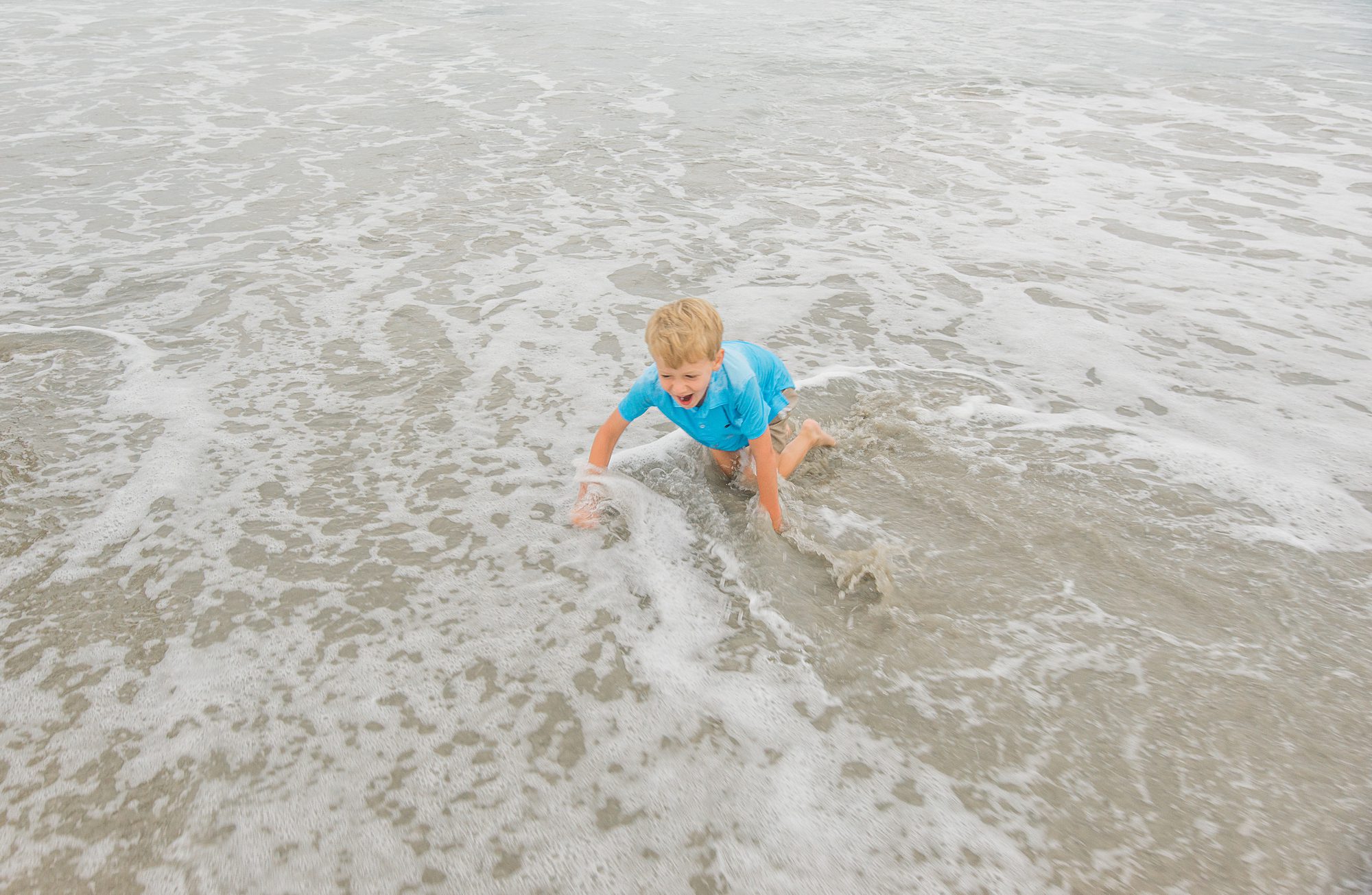 little boy plays in ocean waves 