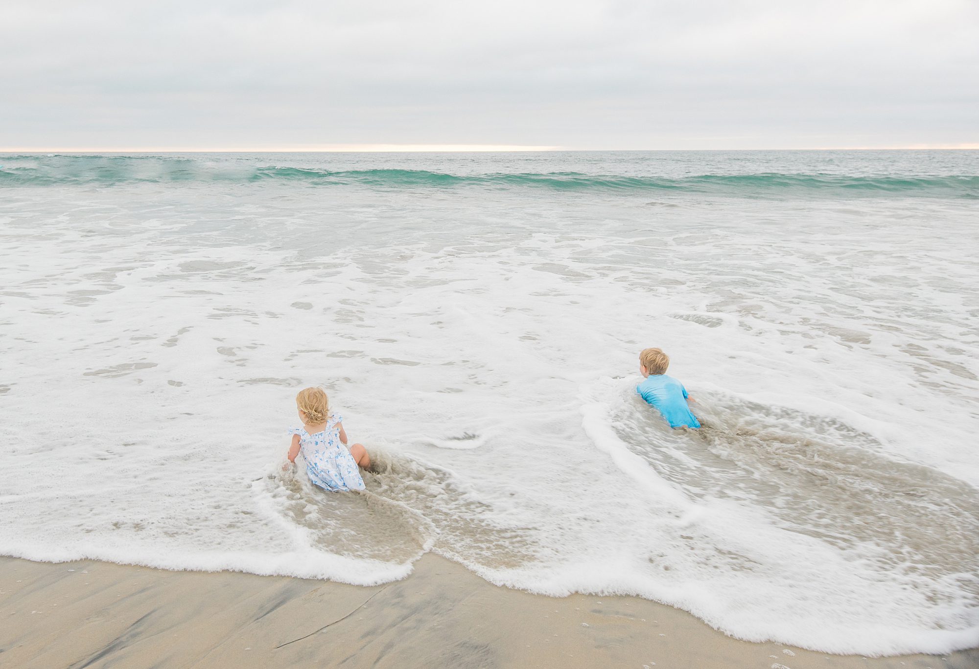 siblings playing in the water at beach in Del Mar, CA