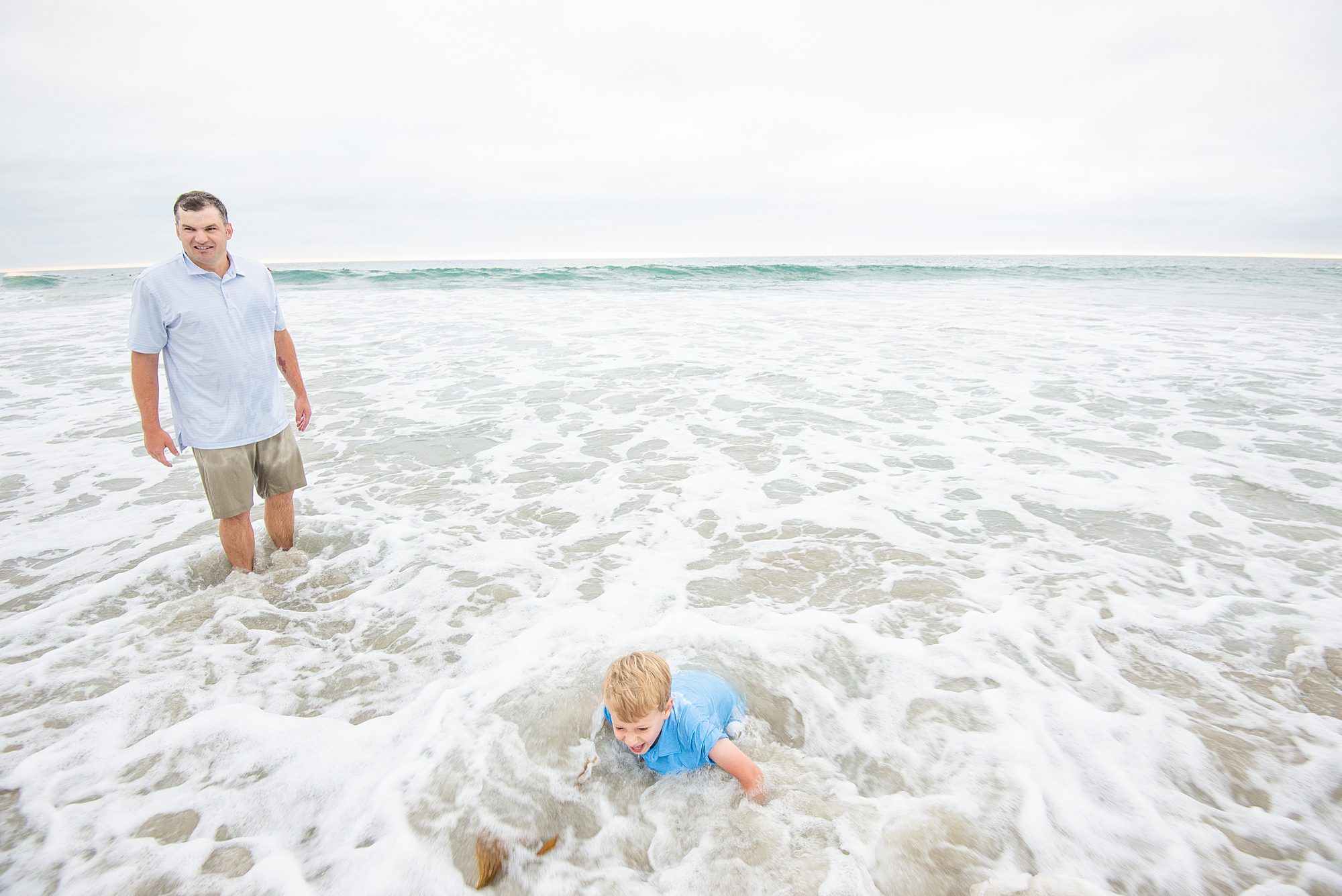 candid portraits of family playing in the ocean