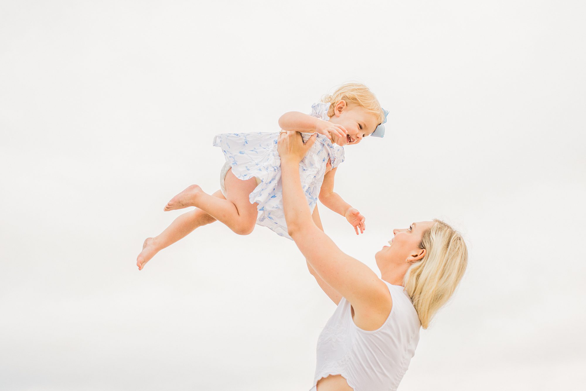 mom holds baby girl up in the air