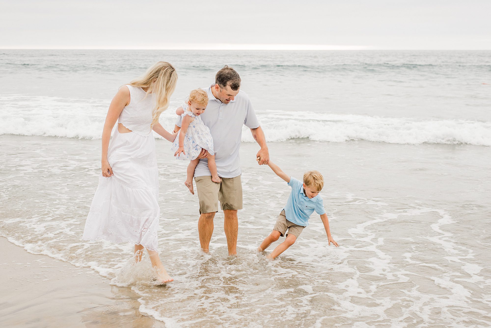family of four walks along Del Mar Beach in CA
